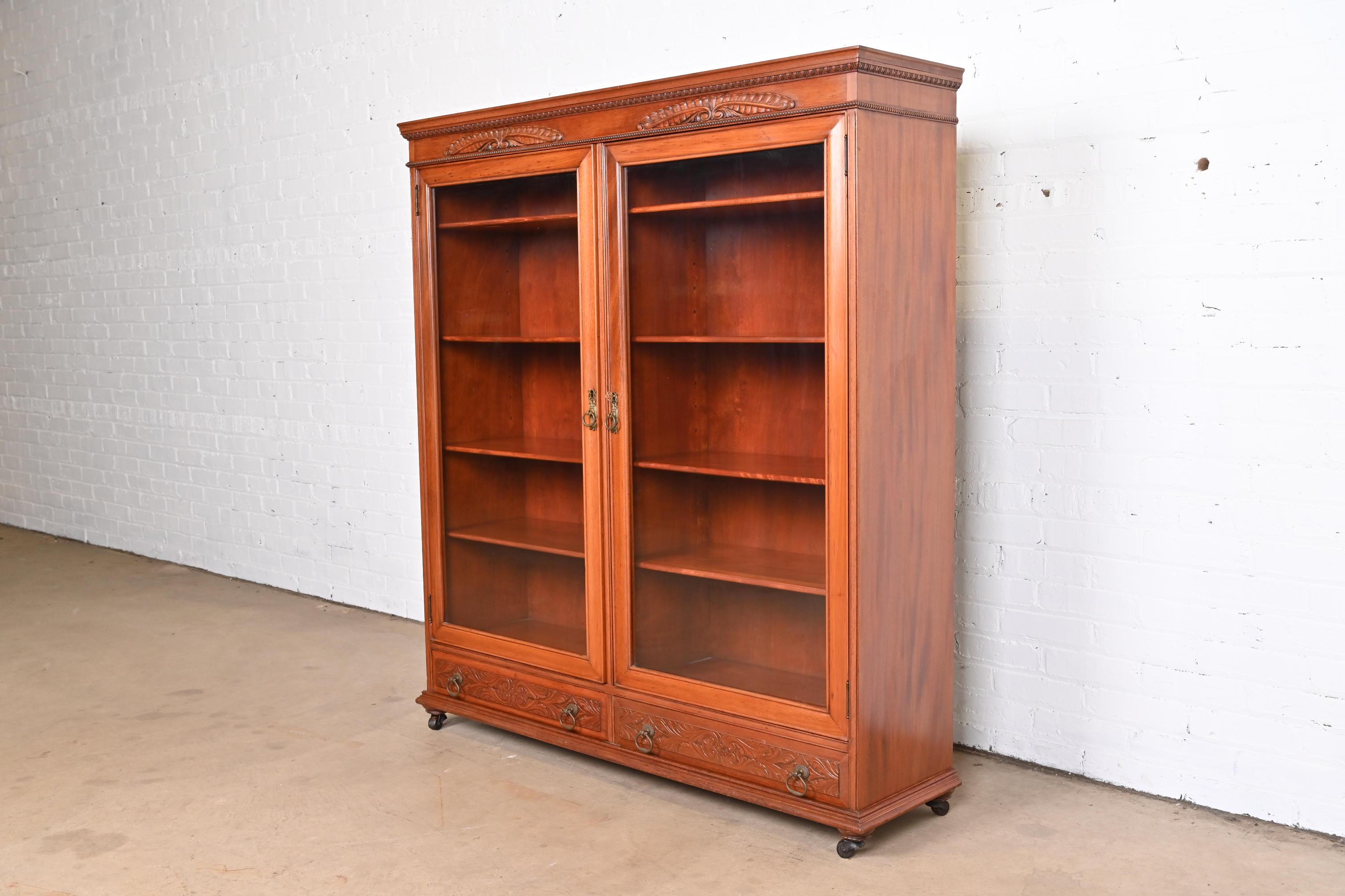 A beautiful antique Victorian double bookcase cabinet 

USA, Circa 1900

Carved mahogany, with glass front doors and original brass hardware. Cabinet locks, and key is included. Interior shelves are adjustable.

Measures: 50.13