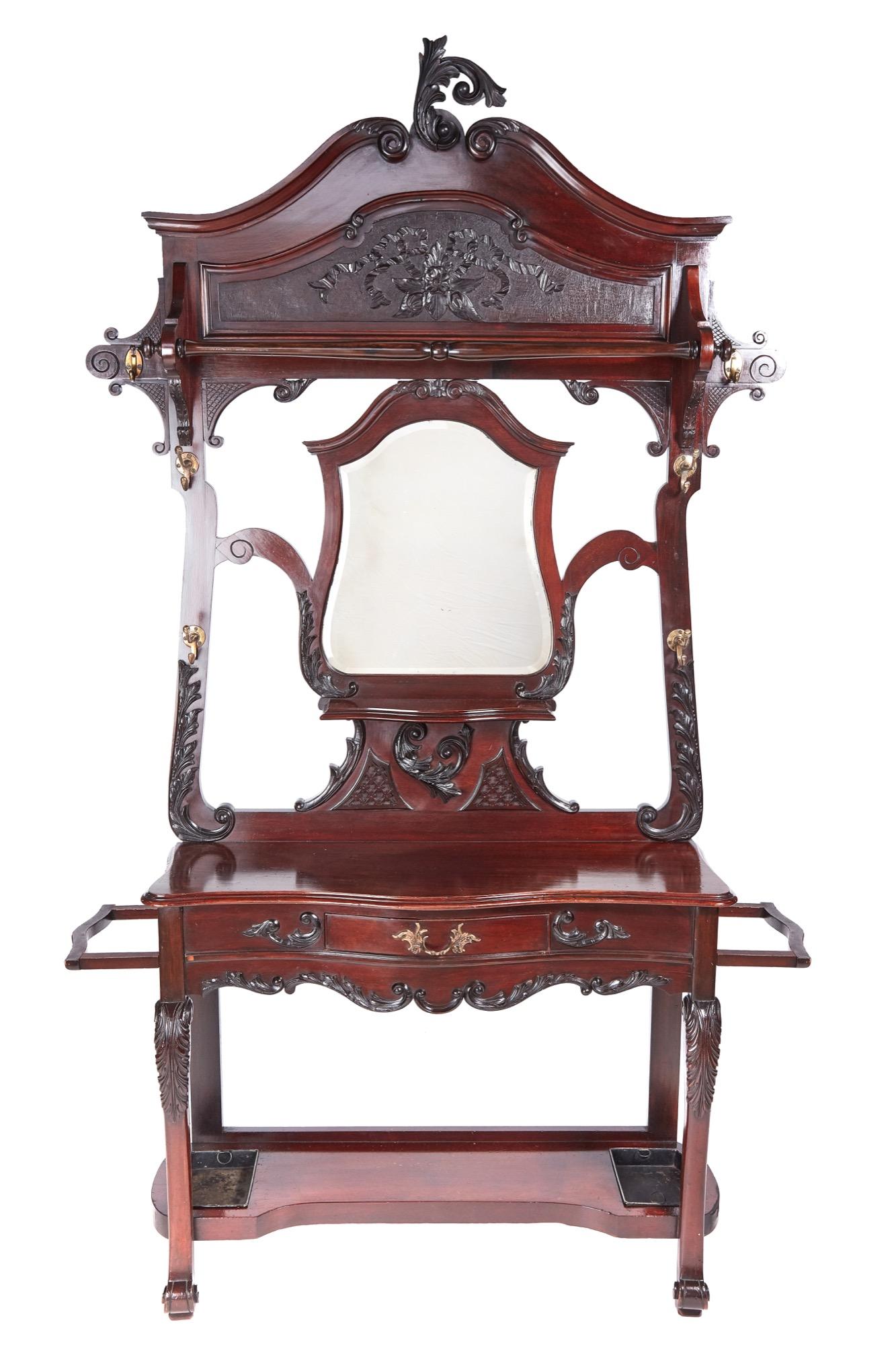 This is a quality 19th century Victorian antique carved mahogany hall stand with a stunning carved top, shaped mirror to the center, original brass hooks, one drawer, shaped stick stand, supported by carved shaped cabriole legs united by a shaped