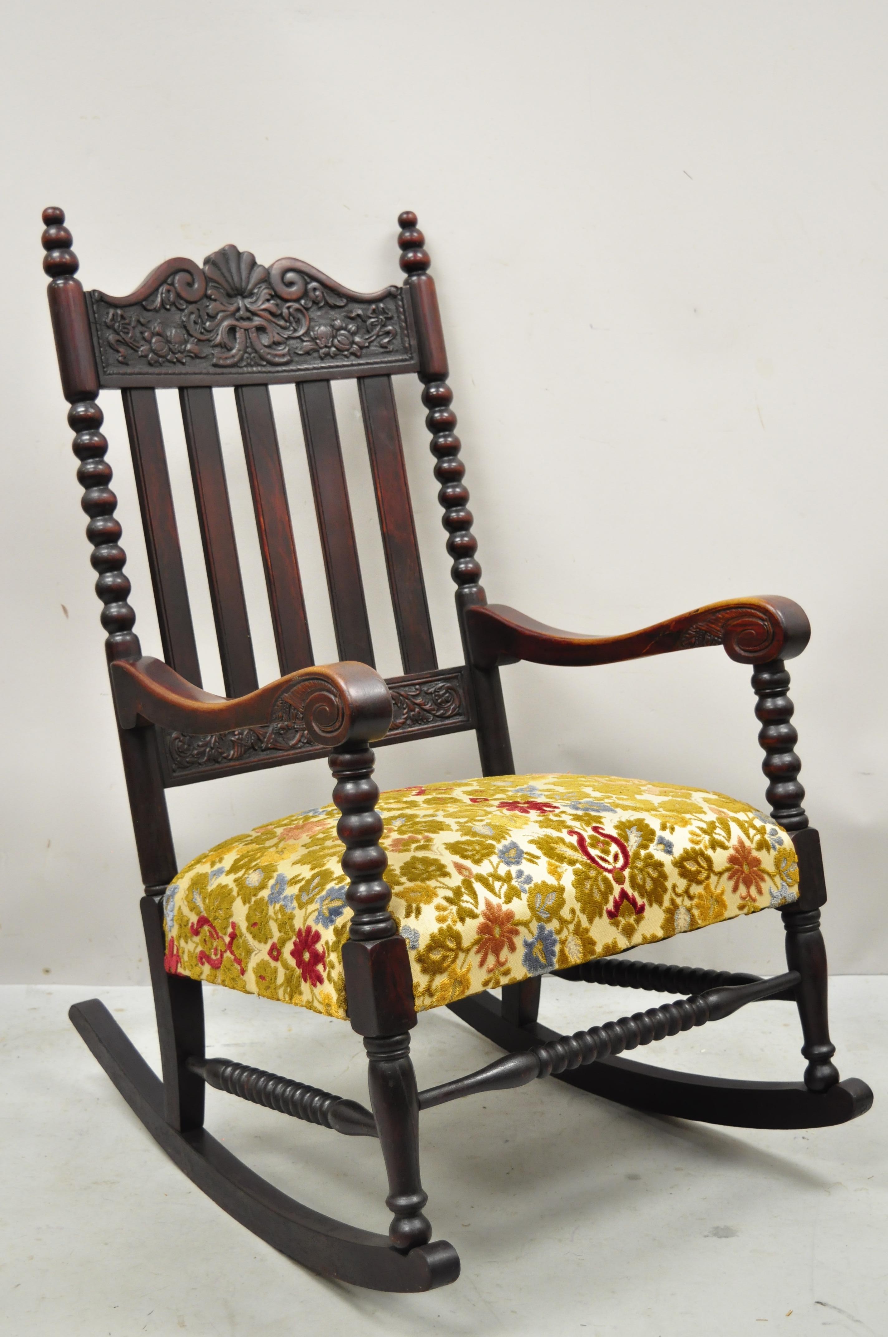 Antique Victorian carved mahogany northwind face and cornucopia rocking chair rocker. Item features carved northwind face to top rail, carved cornucopia lower rail, floral crewel work upholstered seat, 