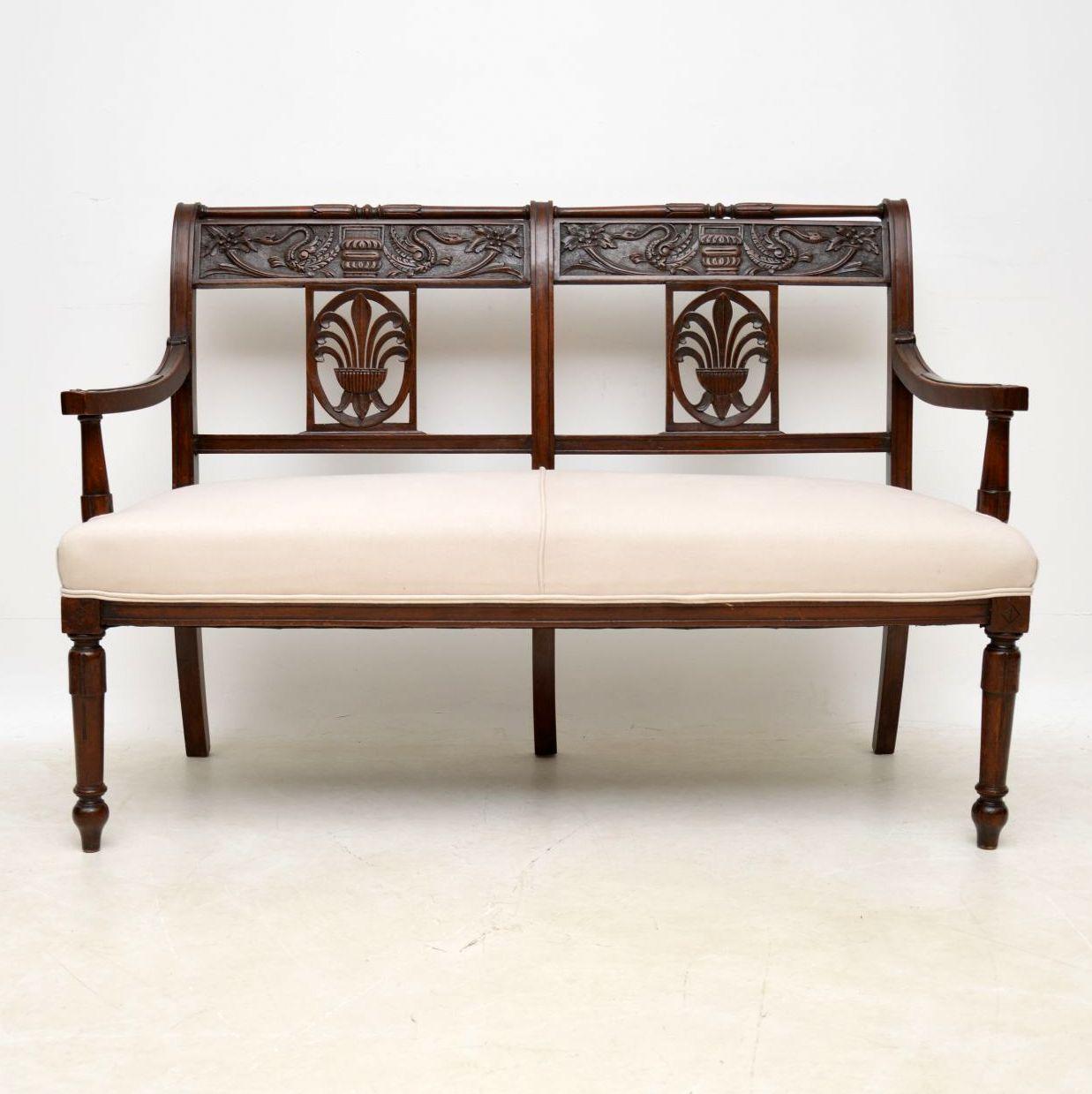 Antique Victorian mahogany upholstered settee with plenty of deep carvings and in good original condition, dating from circa 1860s-1880s period. The back has two carved top rails and some stunning carvings of dragons plus other items and two carved