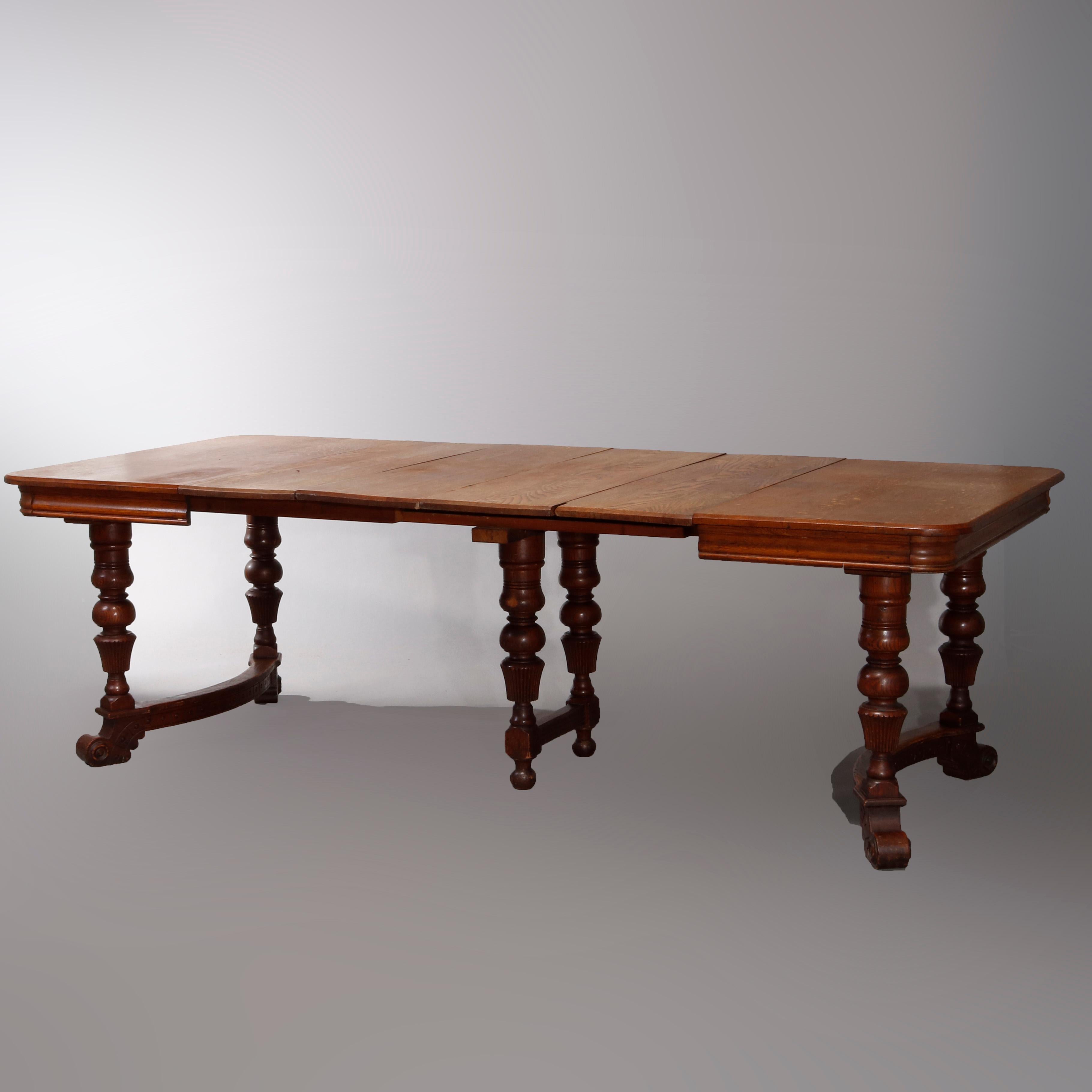 An antique Victorian extension dining table offers oak construction with carved balustrade legs having conve stretchers and scroll feet, includes four leaves, circa 1900

Measures: 28.5