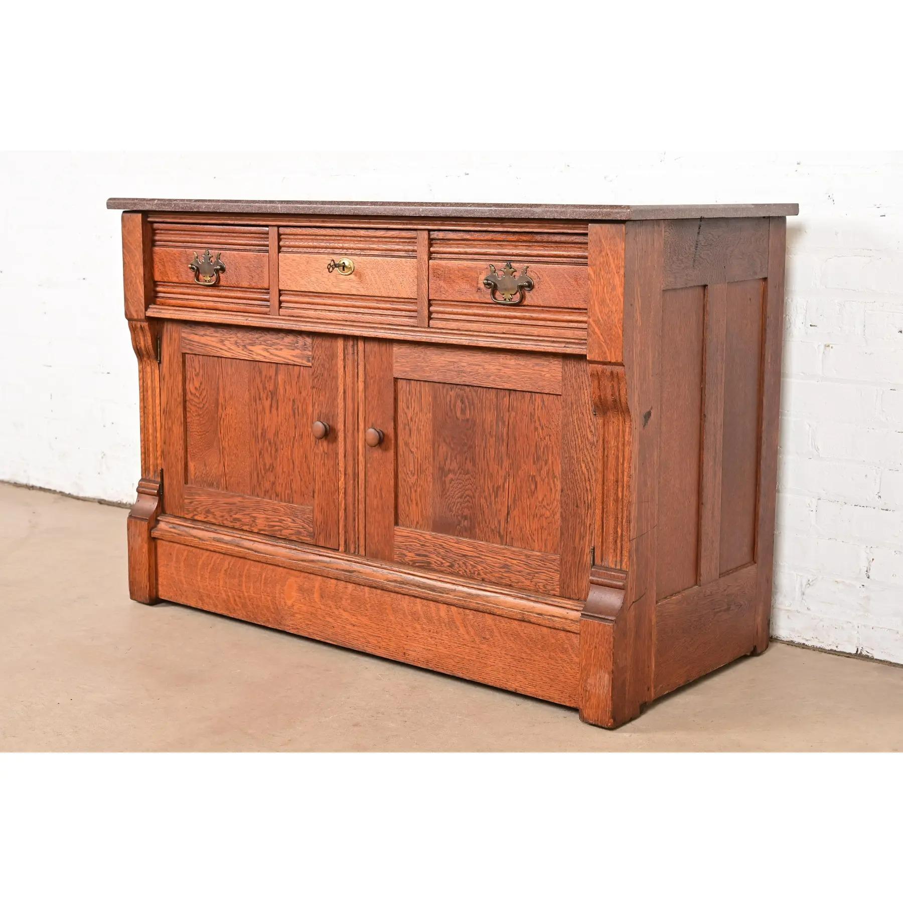 A gorgeous antique Victorian or Arts & Crafts sideboard, buffet server, or bar cabinet

In the manner of Herter Brothers

USA, Circa 1890s

Beautiful quarter sawn oak, with marble top and brass hardware. Top middle drawer locks, and key is
