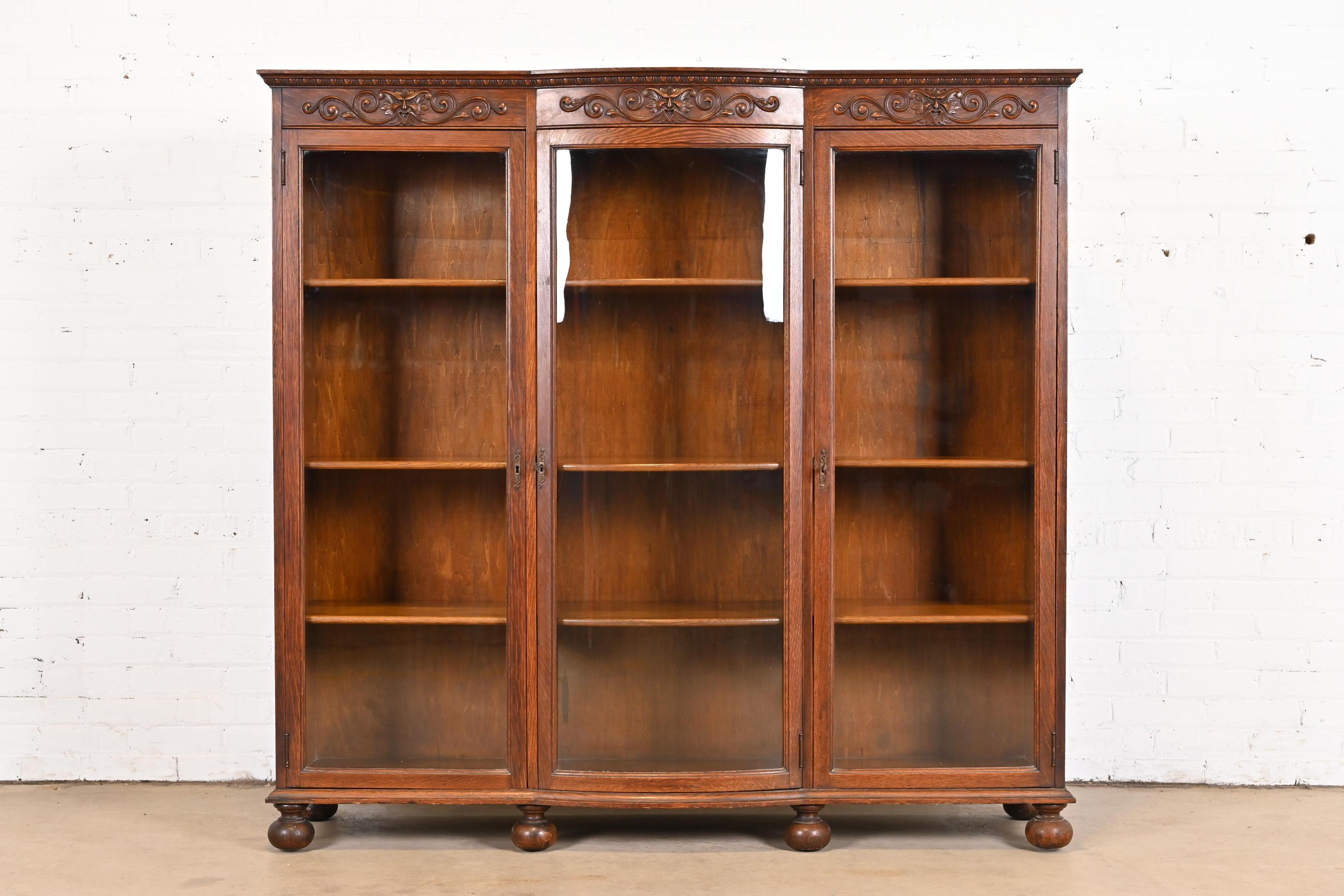 A gorgeous antique Victorian bow front triple bookcase

In the manner of R.J. Horner

USA, Circa 1900

Carved quarter sawn oak, with original glass doors and brass hardware. Cabinets lock, and key is included.

Measures: 63