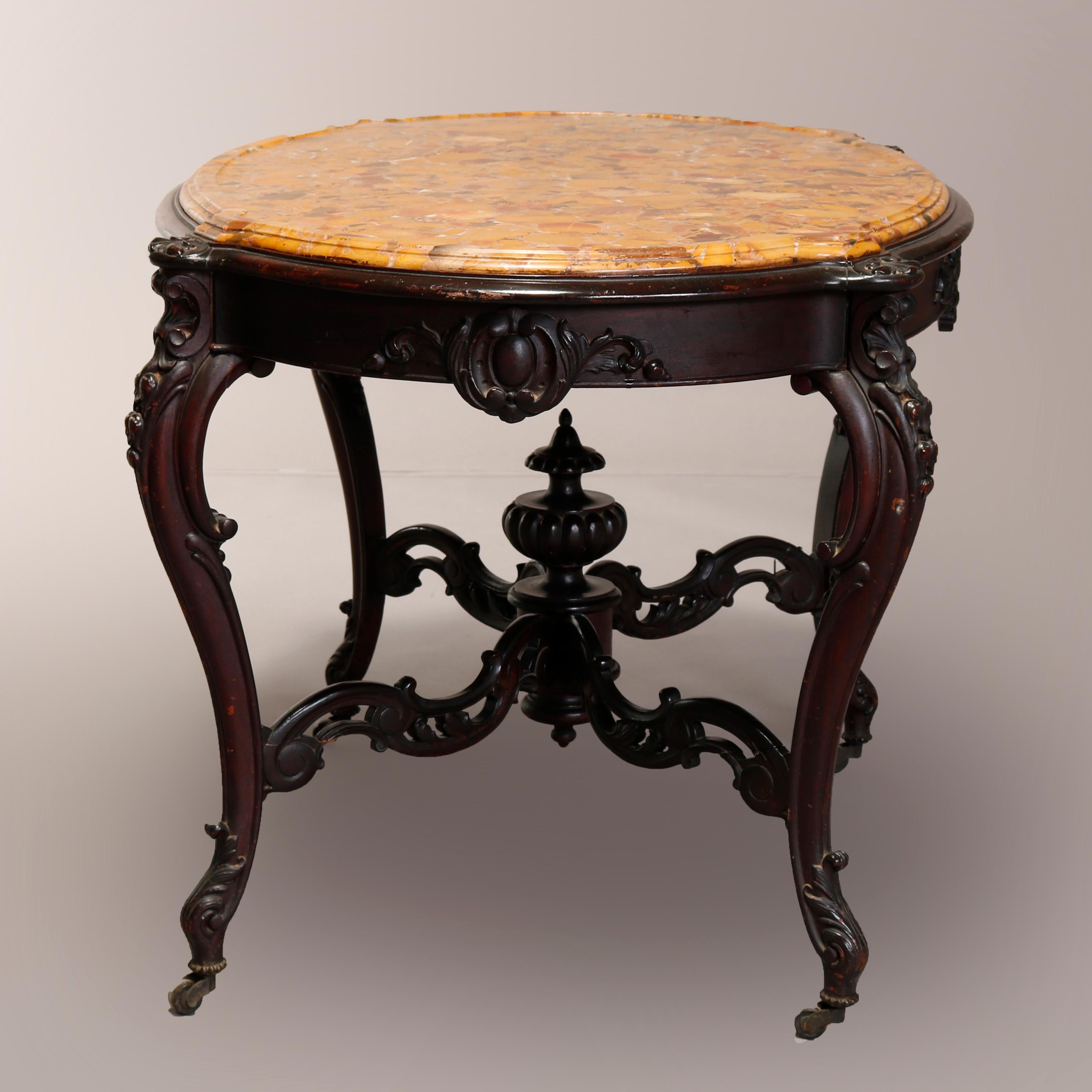 An antique Victorian center table offers shaped fossilized beveled marble top surmounting rosewood base with foliate carved skirt raised on cabriole legs having scroll form stretcher with central finial, carved acanthus elements throughout, circa