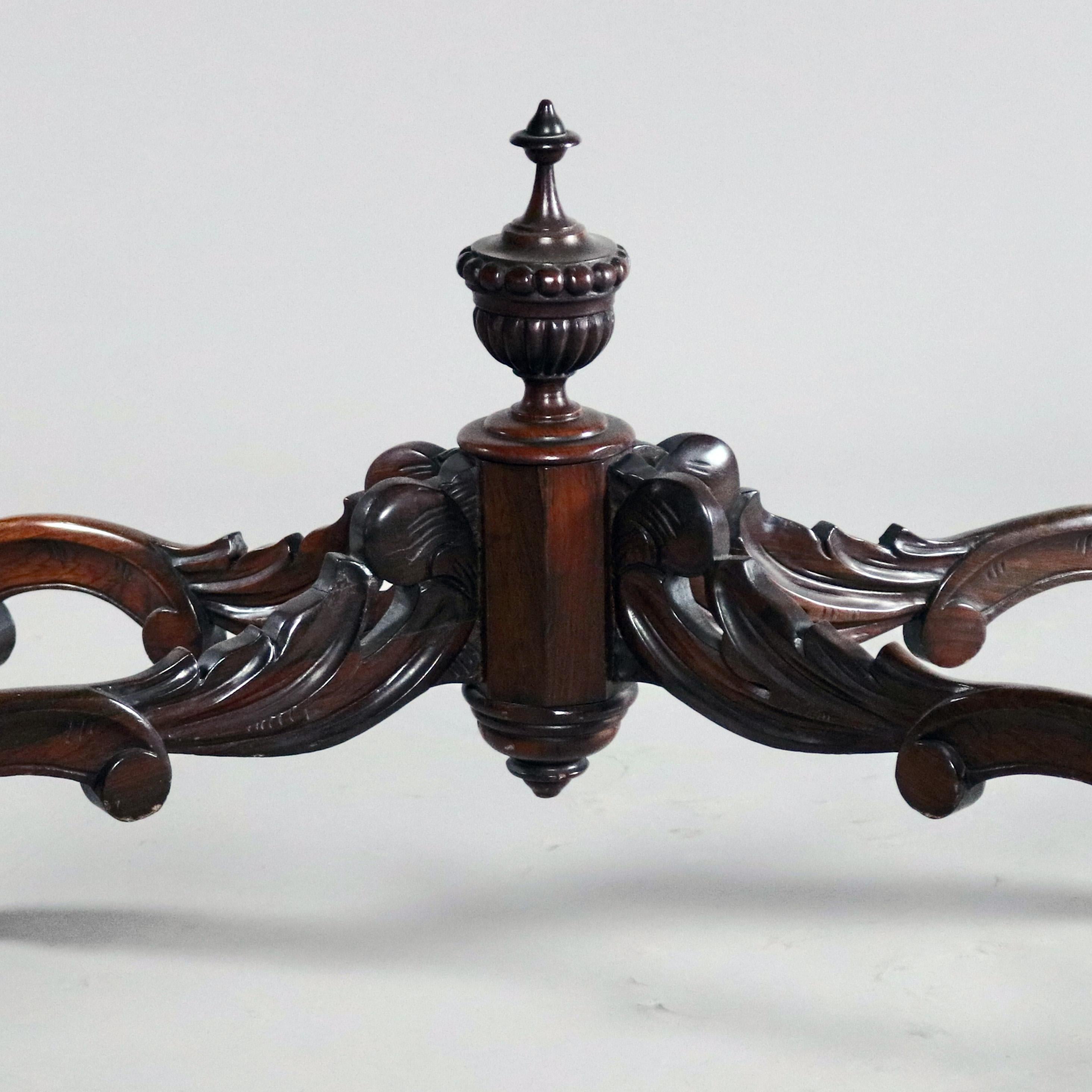 An antique Victorian turtle top centre table features shaped beveled marble top surmounting rosewood base with carved foliate and scroll decorated serpentine apron raised on foliate carved cabriole legs with scroll form cross stretcher having