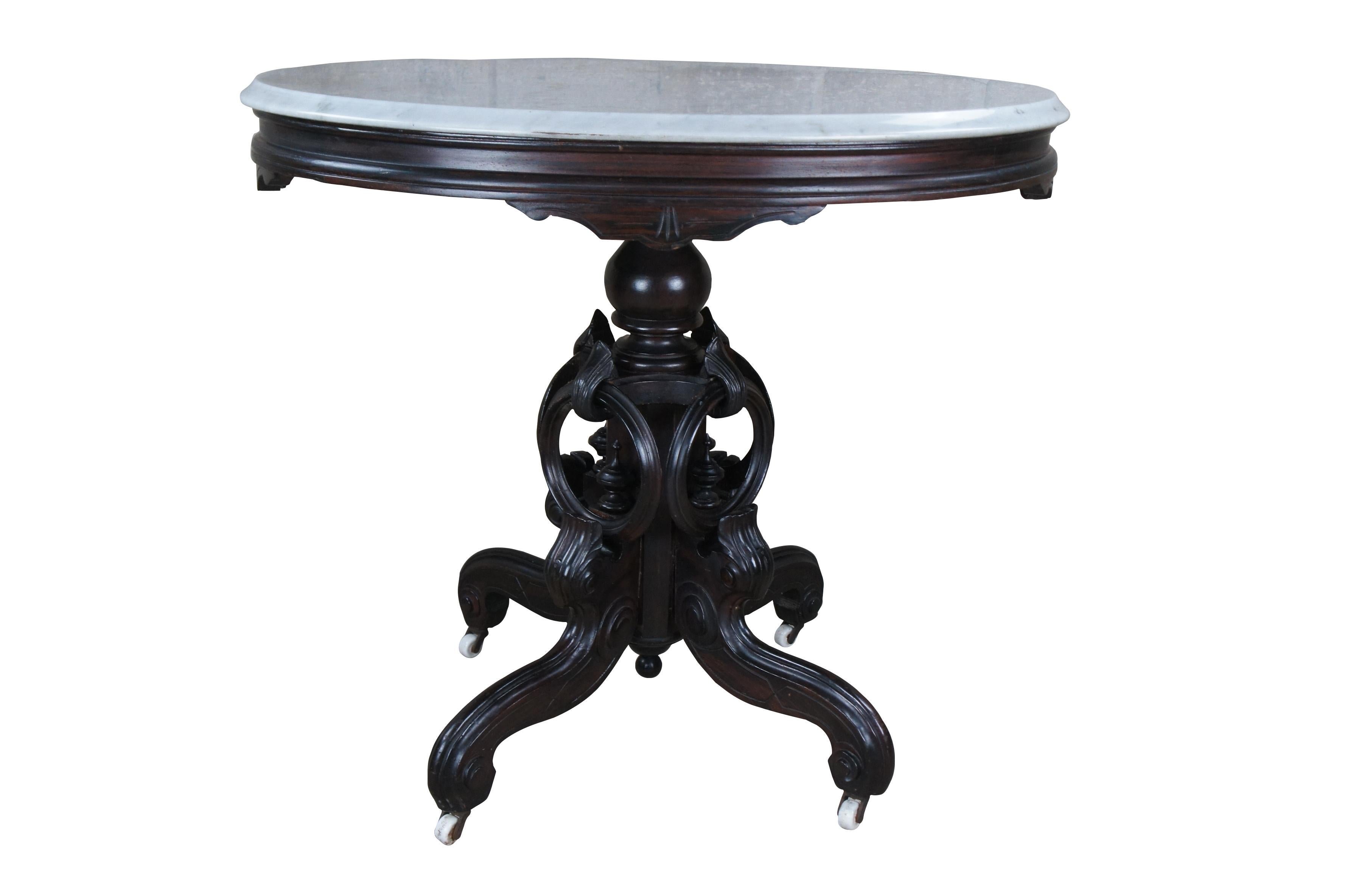 Antique Victorian Eastlake parlor table with Rosewood painted grain finish featuring an oval top with beveled edge over acanthus leaf accents, rings, finials, and serpentine legs.

Made by Chadwick & Sweet of Dayton Ohio, part of the White