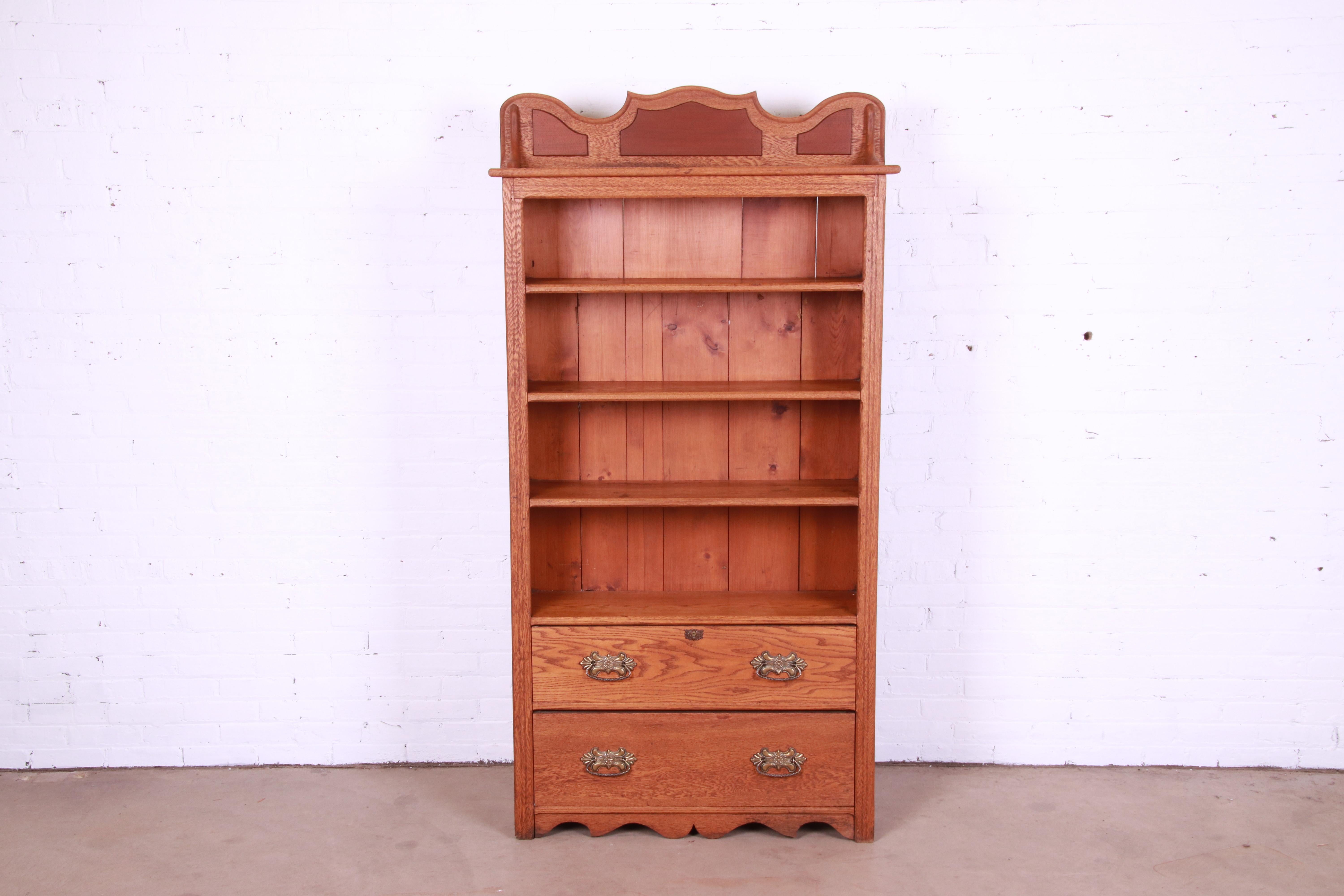 A gorgeous antique Victorian or Arts & Crafts open bookcase with drawers

USA, Circa 1900

Carved solid oak, with original brass hardware.

Measures: 38.5