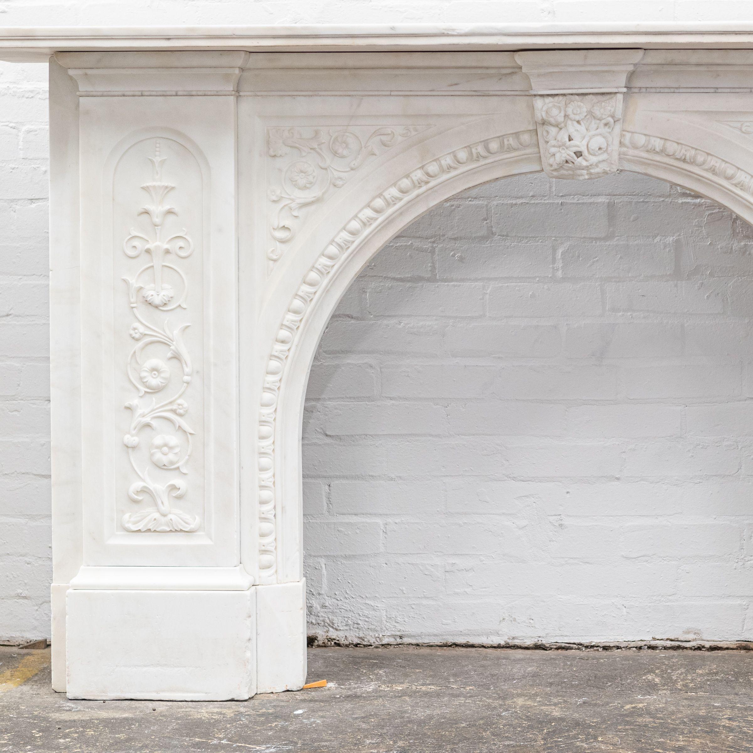A substantial and striking fireplace surround with ornate carvings and crafted from statuary marble.

This original Victorian fireplace features carved floral bouquets repeated down the panelled length of each jamb. The moulded bevelled shelf sits