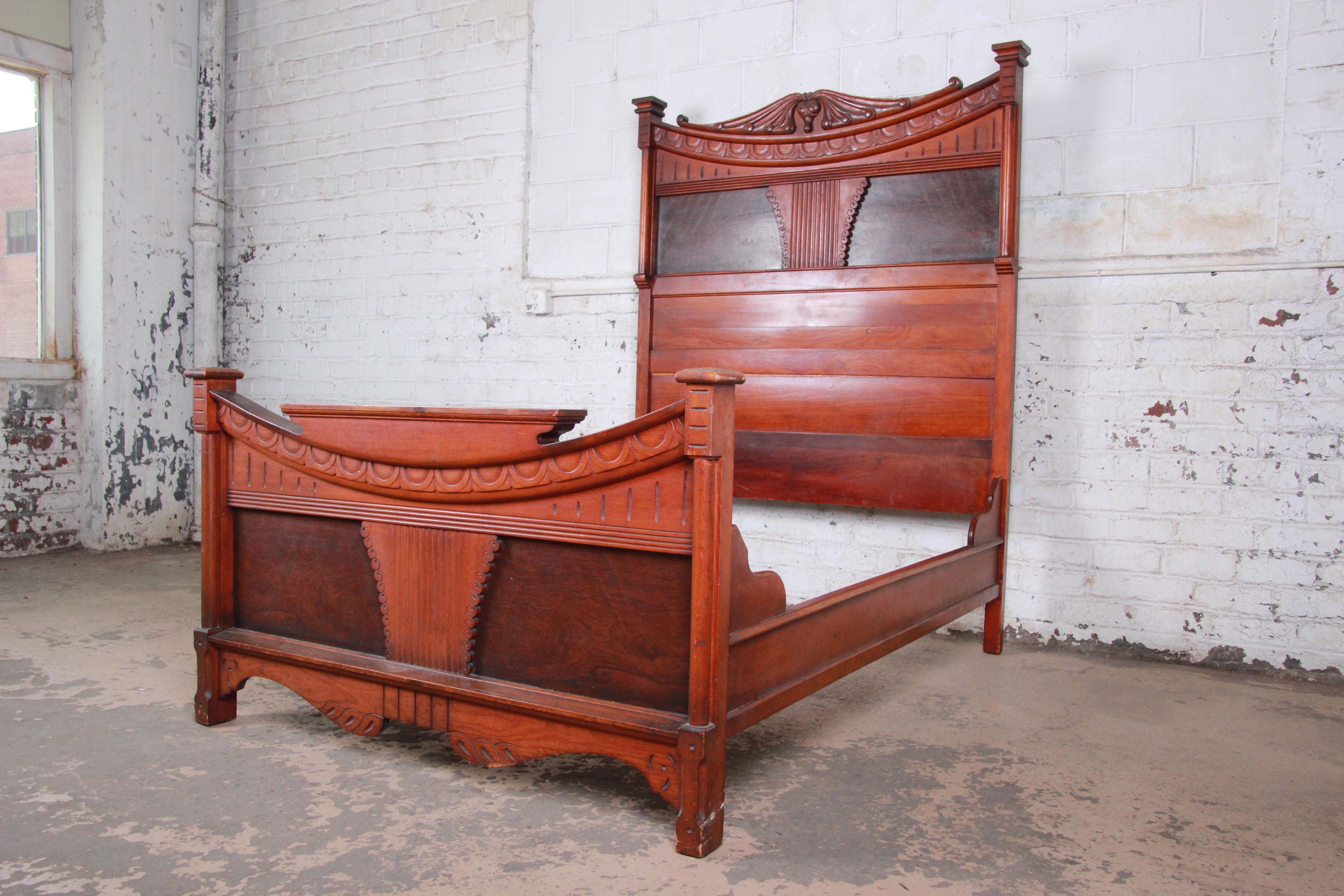 An outstanding 19th century Victorian carved walnut and rosewood full size bed frame. The bed features solid walnut construction with stunning carved wood details and exotic Brazilian rosewood panels on the headboard and footboard. It is in very