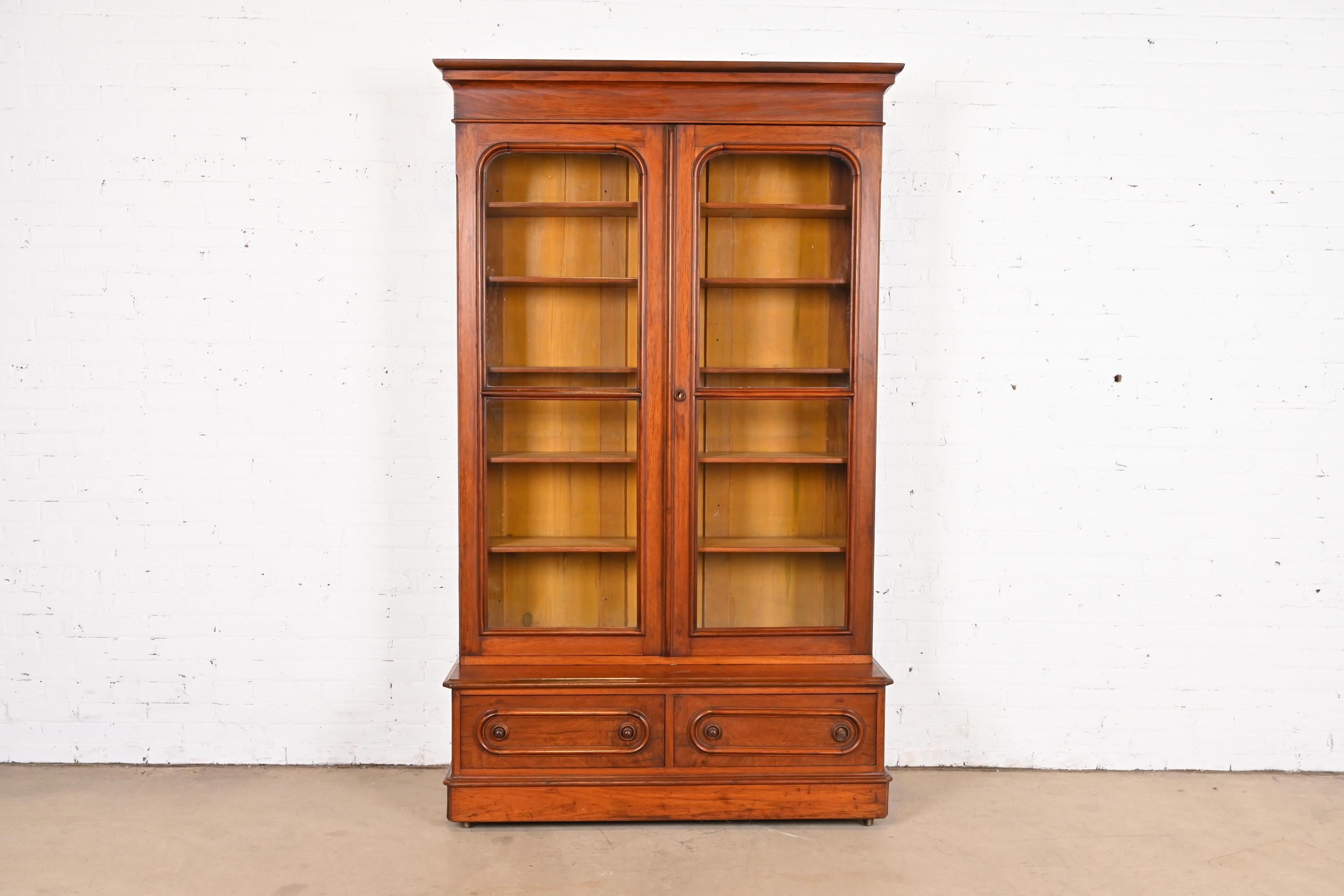 A beautiful antique Victorian two-door step back bookcase cabinet

USA, Circa 1880s

Carved walnut, with glass front doors.

Measures: 50