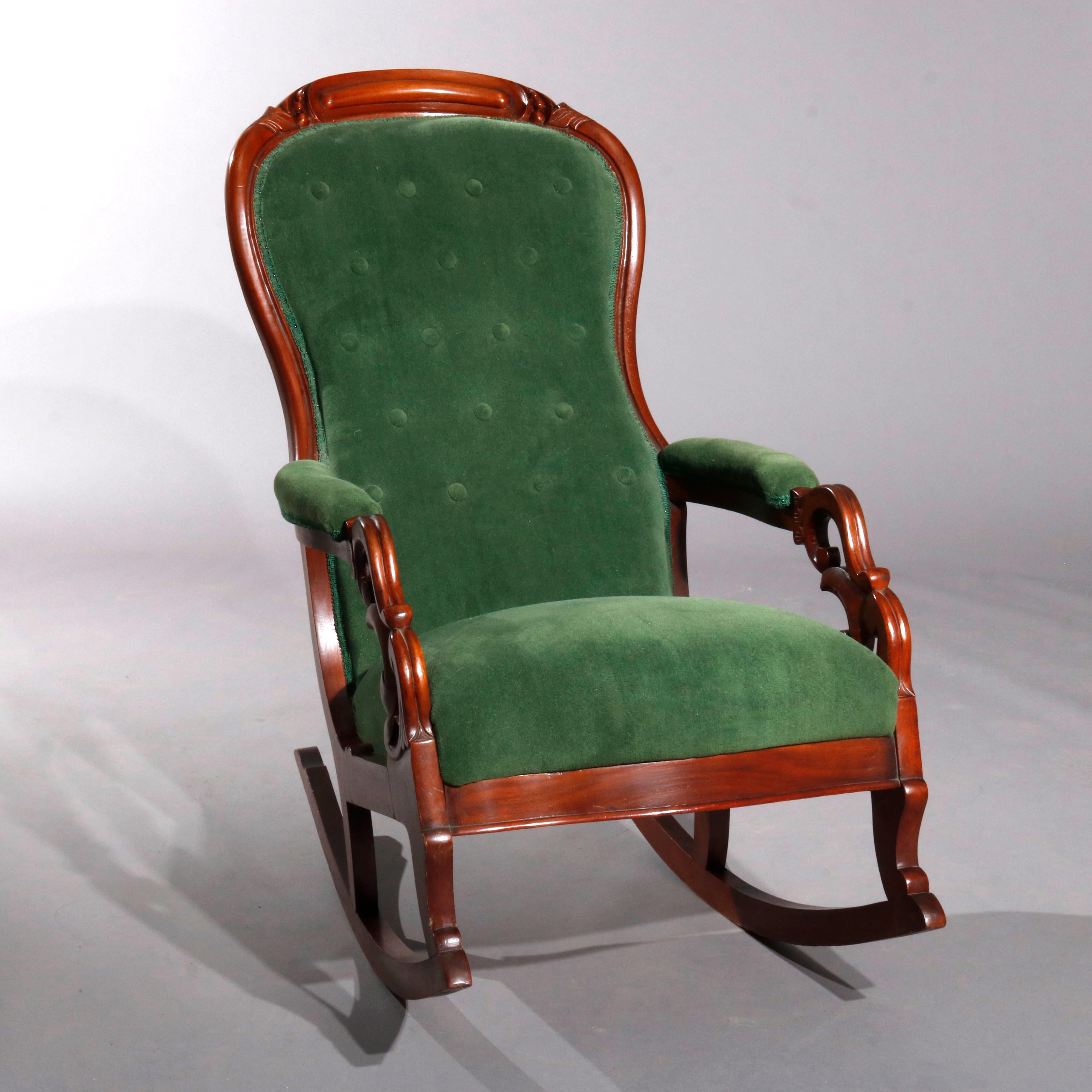 An antique Victorian Lincoln rocking chair offers walnut frame with carved foliate crest surmounting armchair rocker having carved scroll and foliate from frame with upholstered seat, arms and shaped button back, carved arms reminiscent of stylized