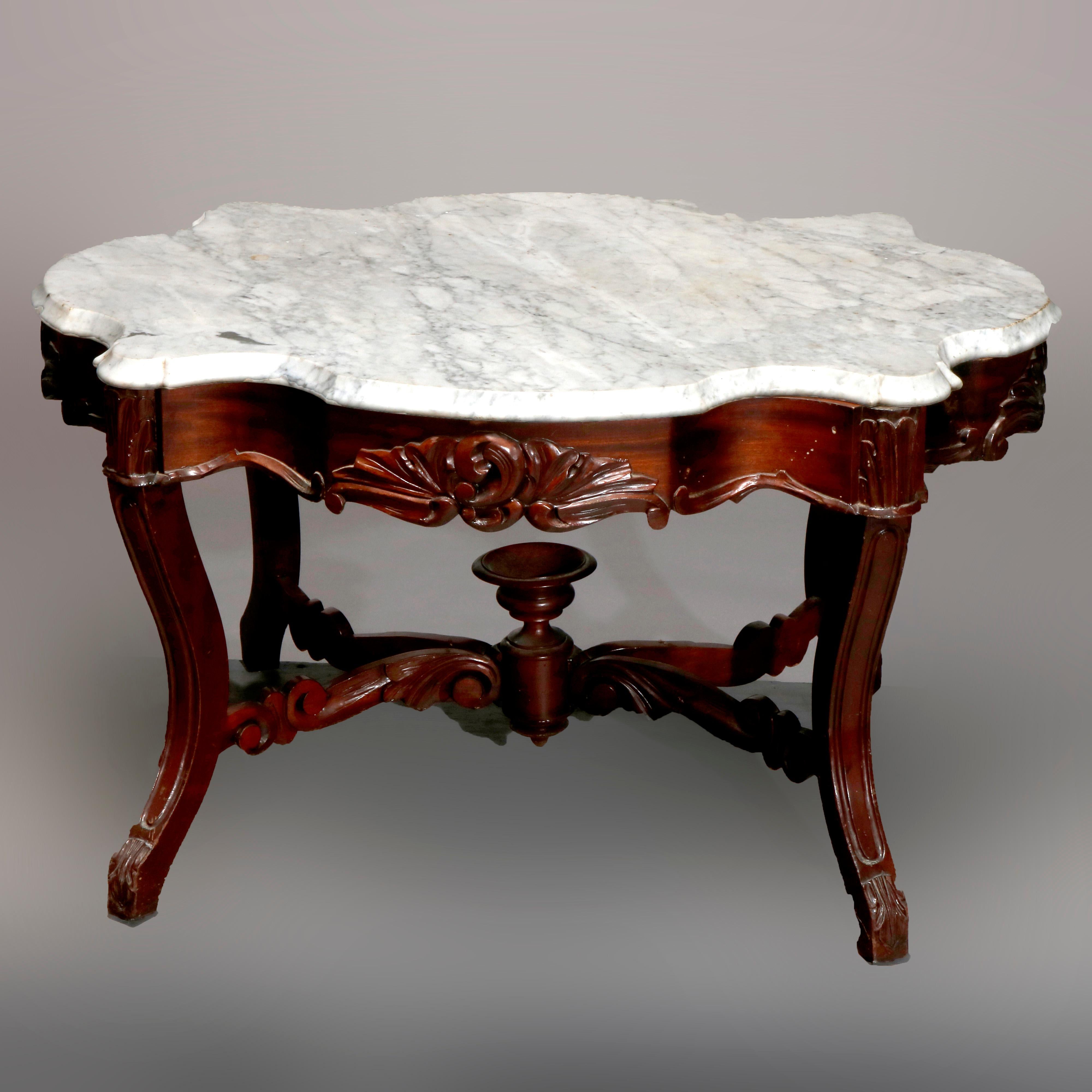 An antique Victorian low coffee table offers shaped and beveled marble turtle top surmounting walnut base having skirt with carved foliate elements raised on convex bowed legs with scroll form stretcher and central urn form finial circa