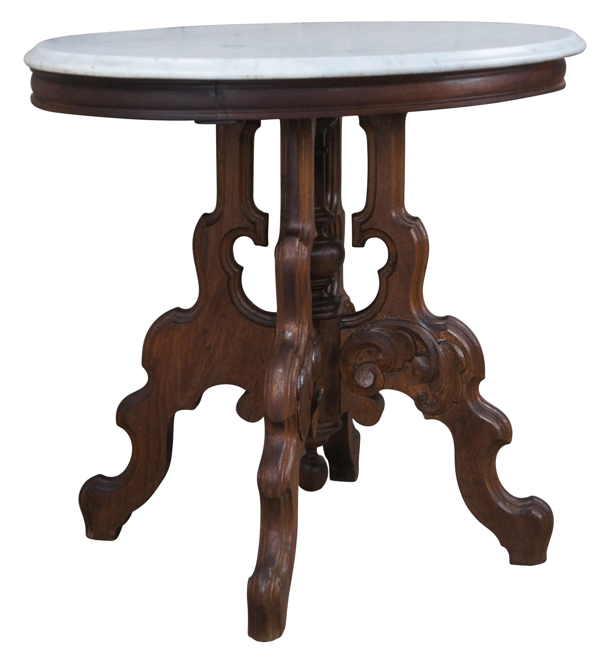 Antique Victorian Eastlake parlor table, circa 1880s. Made from walnut with an oval white marble top. Base features a turned center support surrounded by four serpentine carved legs with floral applied carvings and round down finial.