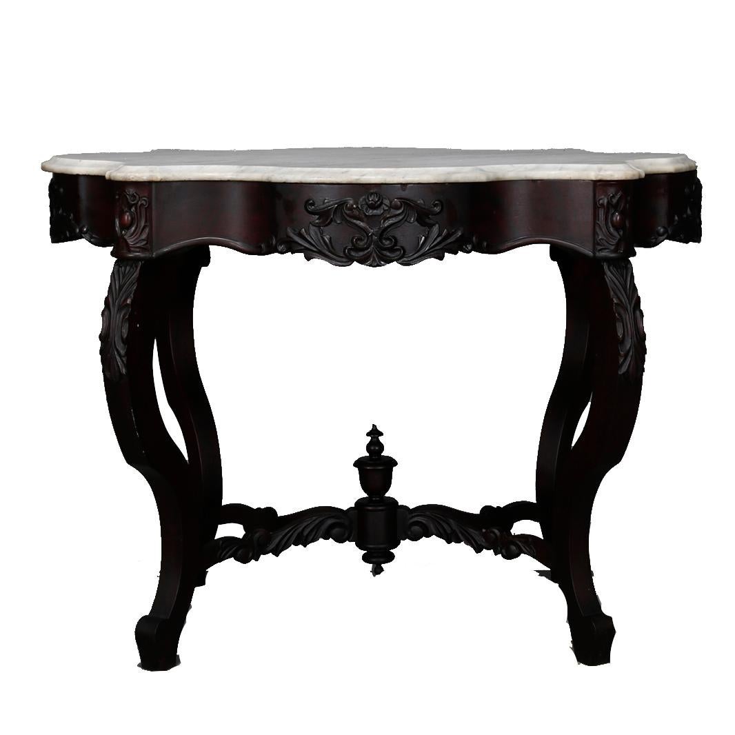 An antique Victorian turtle top center table offers shaped and beveled marble top surmounting walnut base with carved foliate elements, raised on cabriole legs with scroll and foliate form stretcher having central finial, circa 1890

Measures: