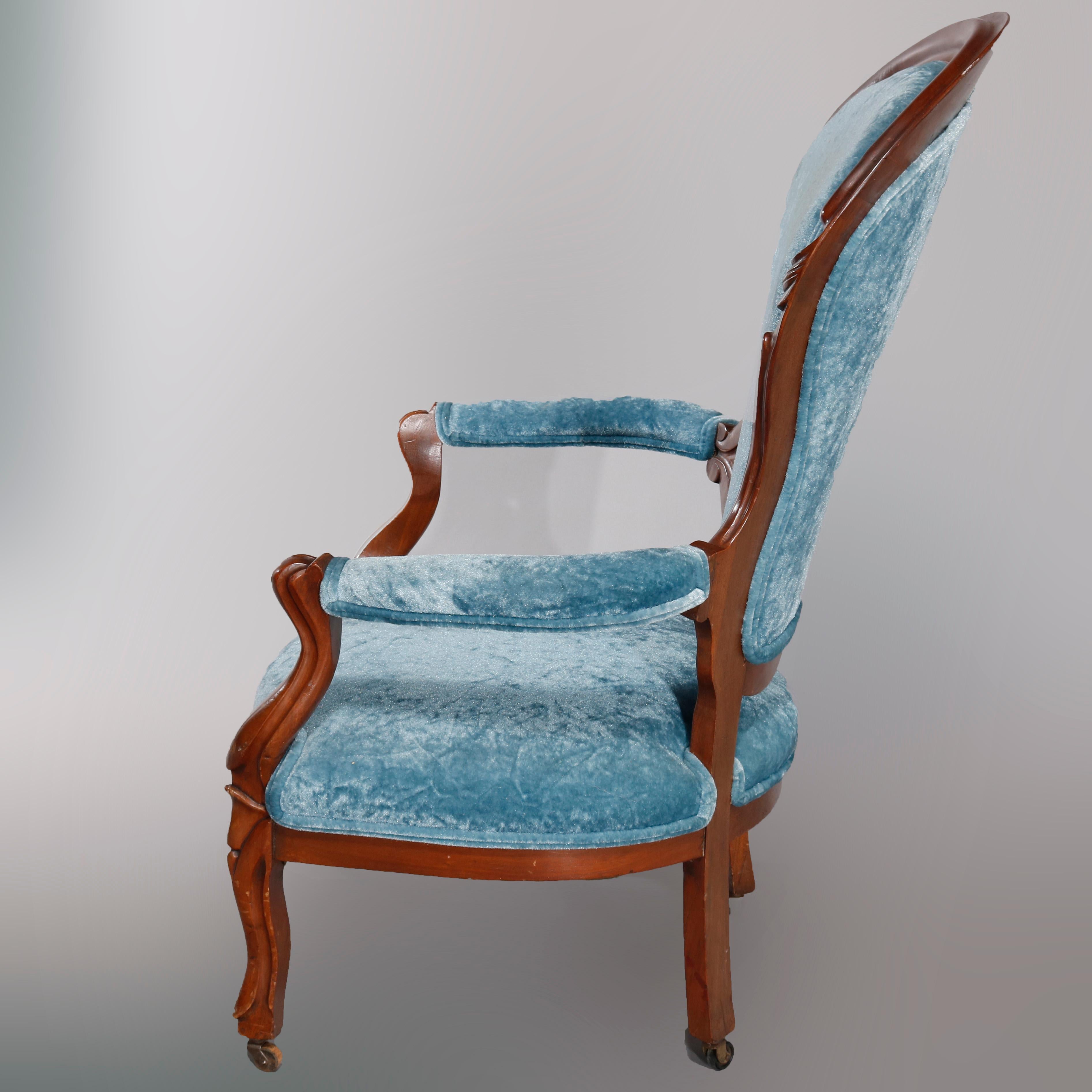 An antique Victorian gentleman's parlor armchair offers walnut frame with carved foliate elements on shaped back surmounting covered scroll form arms and raised on cabriole legs, upholstered seat and back, circa 1890

Measures: 43.25