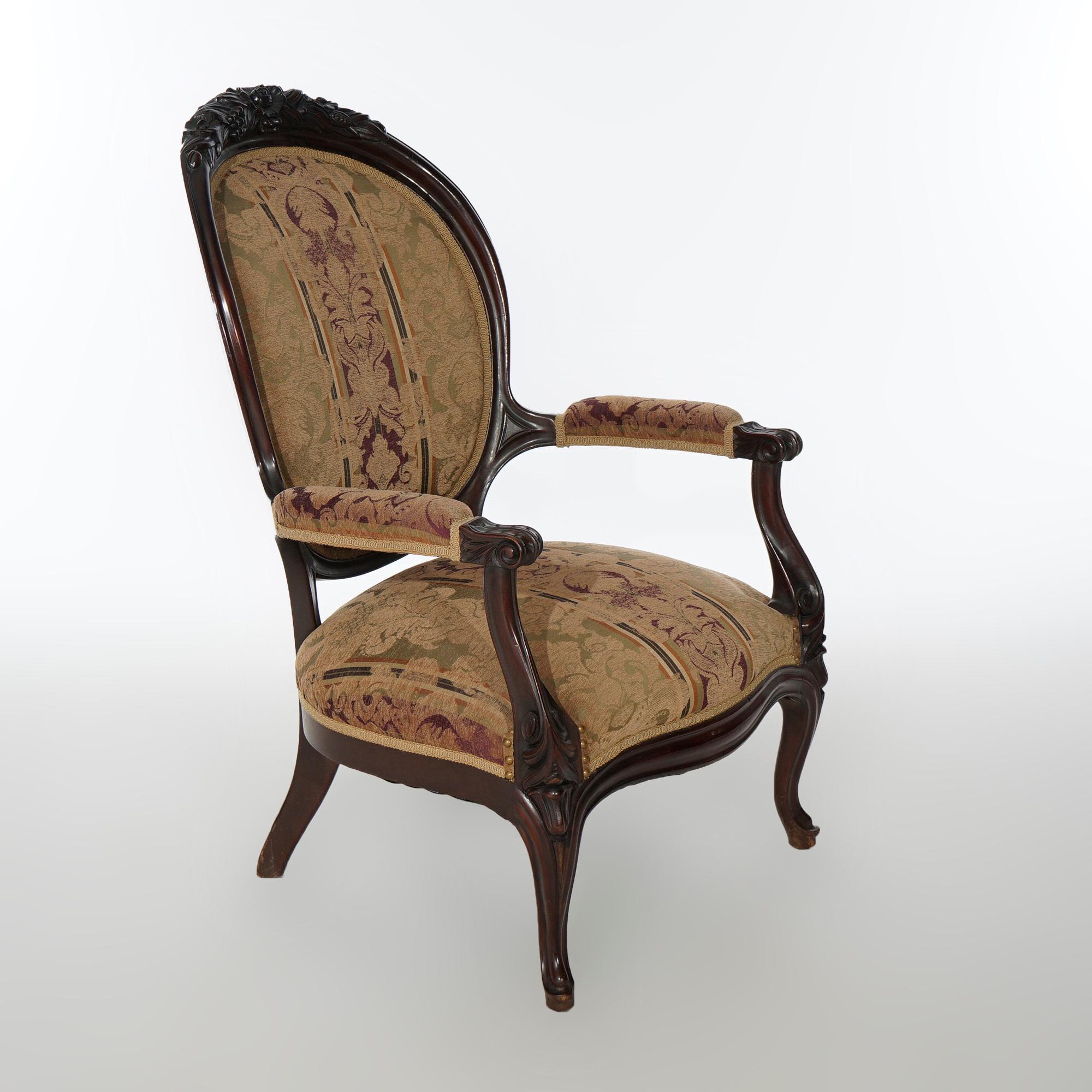 An antique Victorian parlor arm chair offers walnut frame with foliate carved crest over upholstered medallion form back and seat, scroll form arms and raised on cabriole legs, c1890

Measures- 40.5''H x 26.75''W x 30''D; 15'' seat height