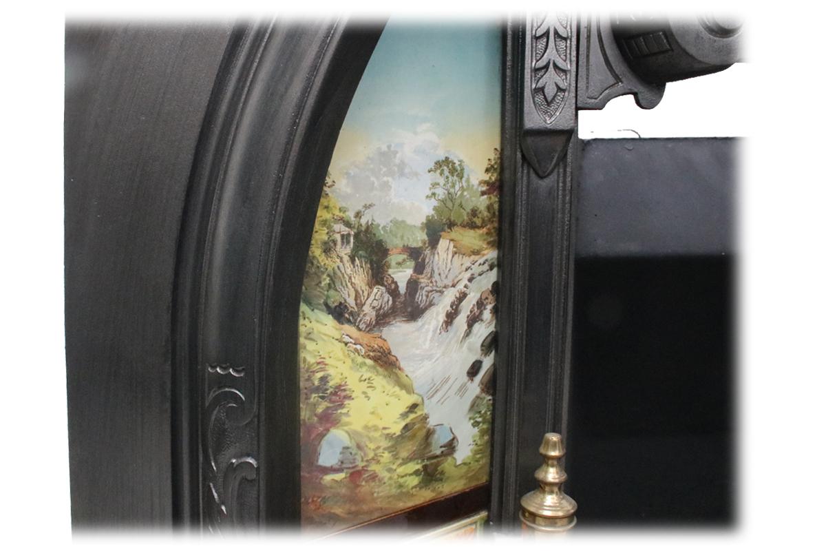 Large antique Victorian cast iron arched fireplace insert with unusual original vertical tile panels displaying hand painted landscape scenes. The left tile is a painting of The Hermitage a National Trust for Scotland protected site in Dunkeld. The