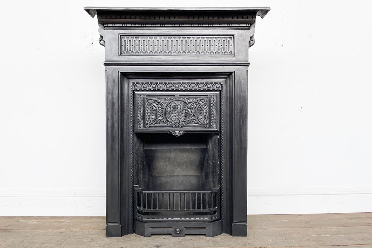 Tall antique Victorian cast iron combination fireplace with a reeded detail across the frieze and ornate blind fret detail to the canopy.

This fireplace has been finished with traditional black grate polish and is supplied with a new clay