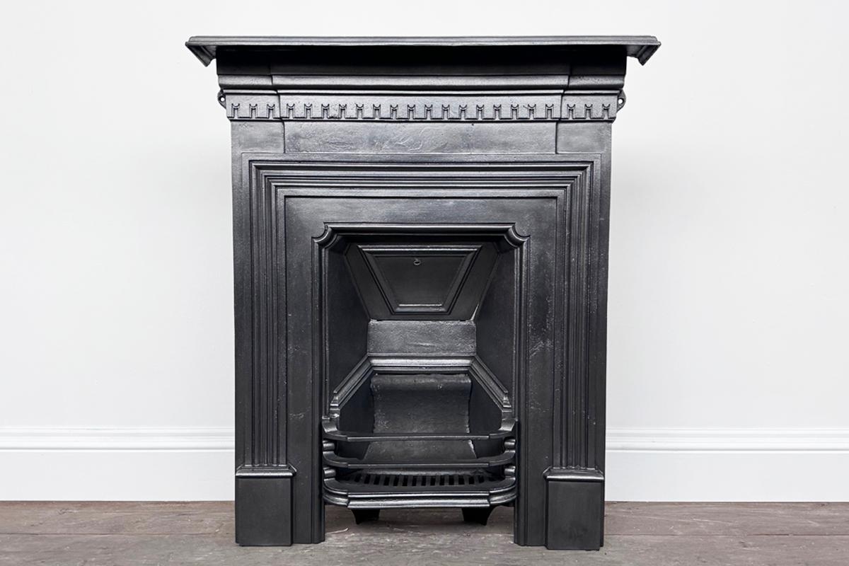Antique Victorian cast iron combination fireplace. with slim reeded moulding framing the fire grate and dentil moulding crossing the breakfront frieze. Circa 1890.

Finished with traditional black grate polish ready for a solid fuel fire once