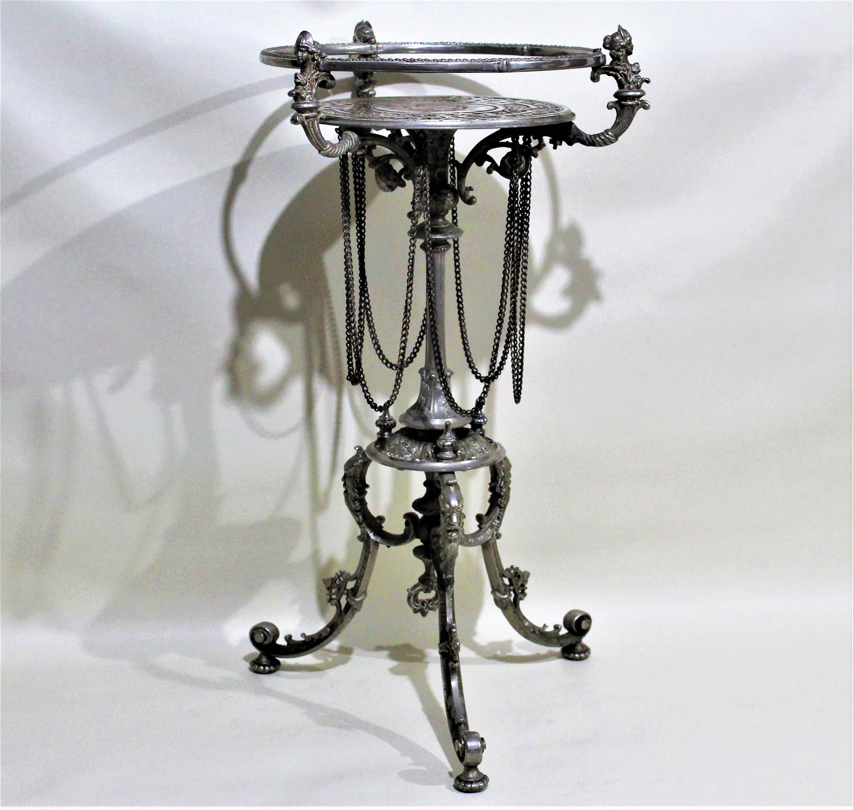 Antique Victorian ornately cast and plated pedestal table with detailed figural accents adorning the supports to the table's gallery top and legs. The top is engraved with a deep scrolled motif. One of the three finial shaped caps from the lower