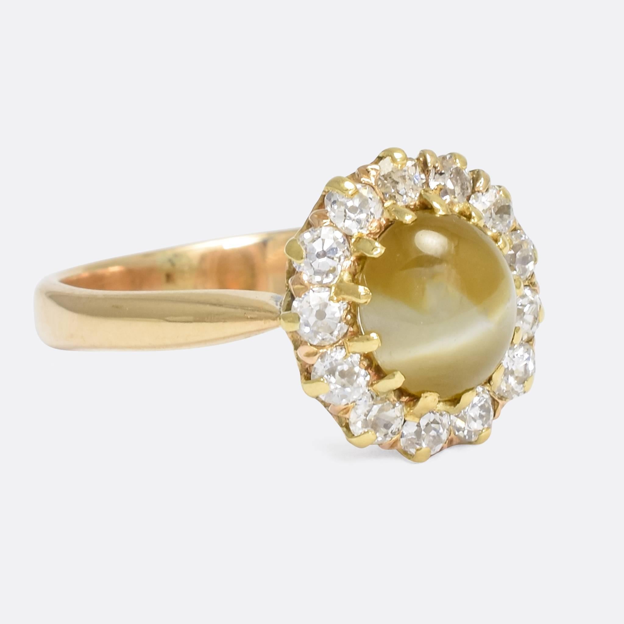 A fine Victorian cluster ring set with a stunning cat's eye chrysoberyl within a halo of old cut diamonds. The principal stone displays excellent chatoyance, with a fine white line appearing to move across the face of the gem. The diamonds are clean