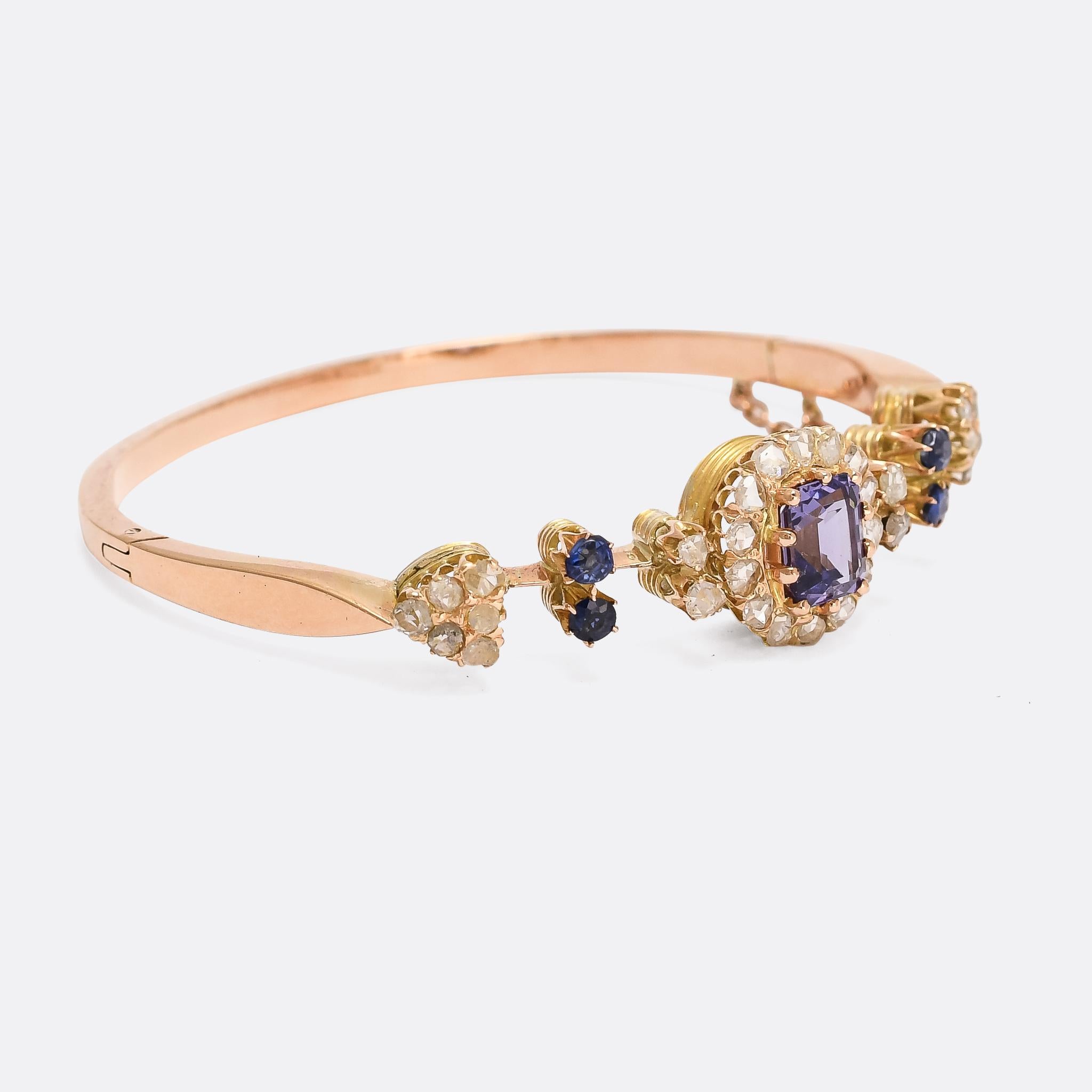 A stunning antique bangle set with vibrant blue spinels and rose cut diamonds. The central stone, set within a diamond halo, is certified at 2.7 carats natural intense blue spinel with no indications of heat treatment and no visible inclusions; it's
