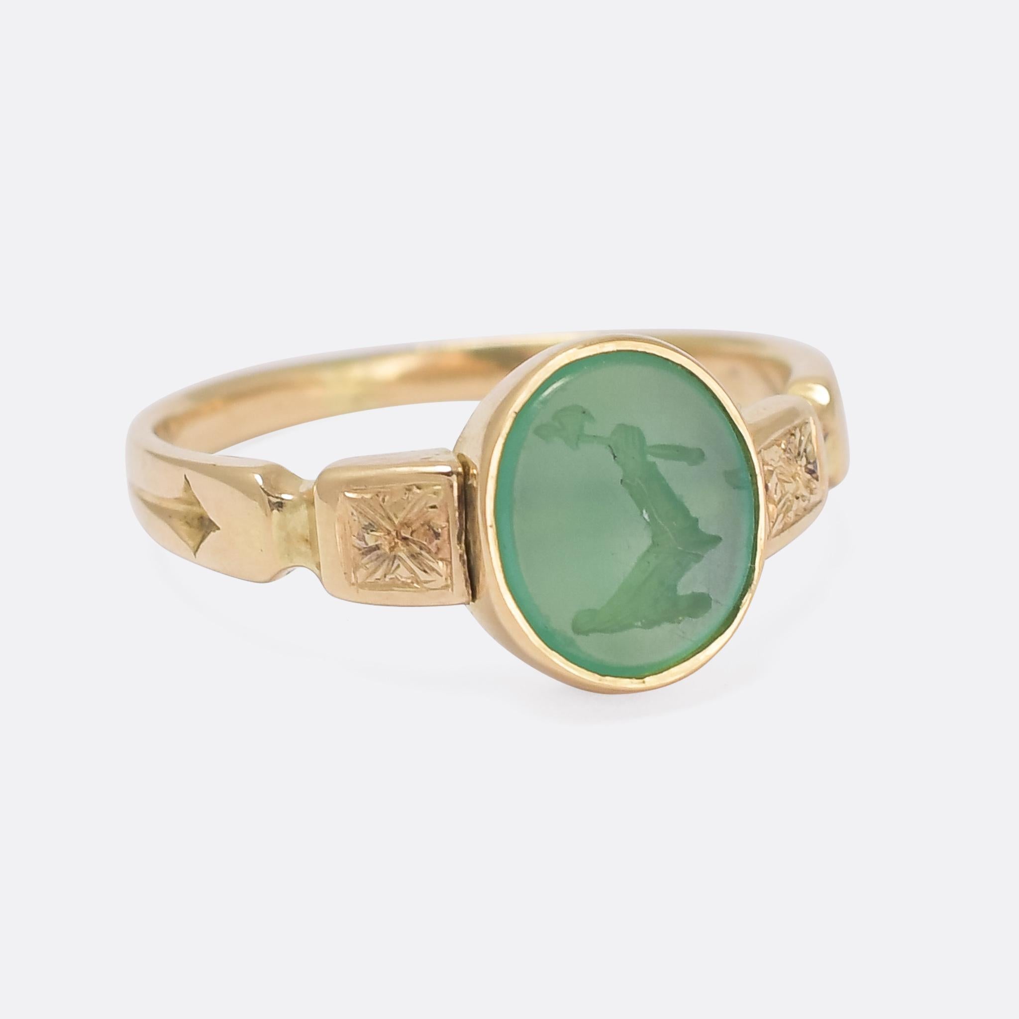 A cool Victorian signet ring set with an intaglio carved green agate heraldic crest depicting an outstretched arm, in full armour, holding a battle axe. The reverse has been reverse carved with the Latin words NON IMMEMOR, or 