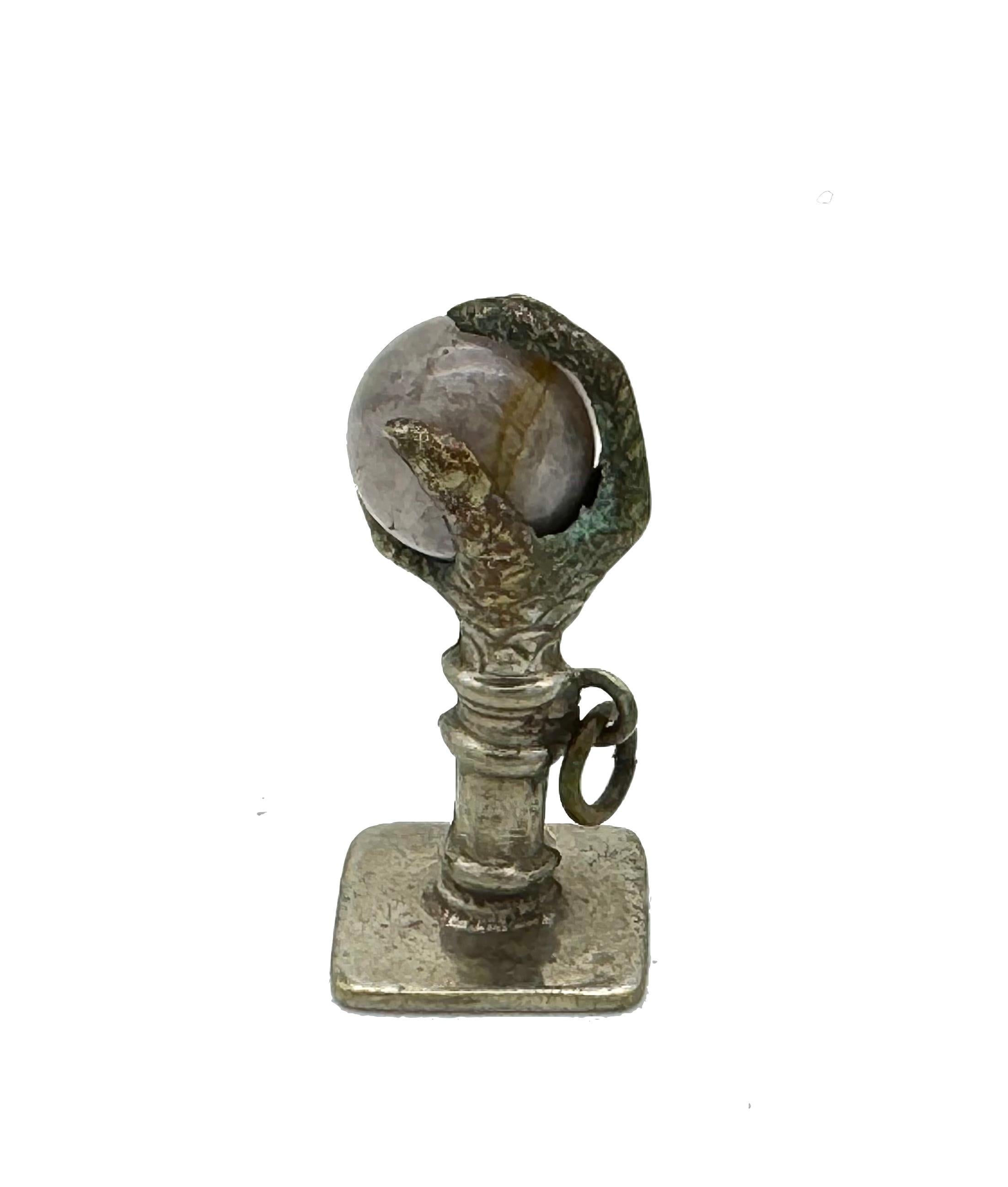 Cette breloque ancienne a été créée dans le dernier quart du XIXe siècle en métal. Le pendentif représente la griffe d'un oiseau de proie tenant une boule de fluorine. La griffe aux formes naturelles est posée sur un piédestal qui repose sur une