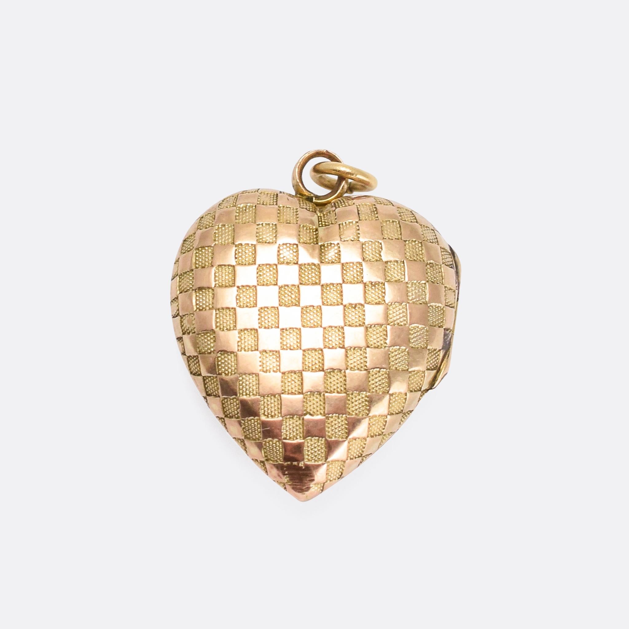 A sweet antique heart locket dating from the late Victorian era, circa 1900. Modelled in 9 karat gold, the front and back are both decorated with a chequerboard design – alternating rows of textured and shiny squares. It opens to reveal two internal