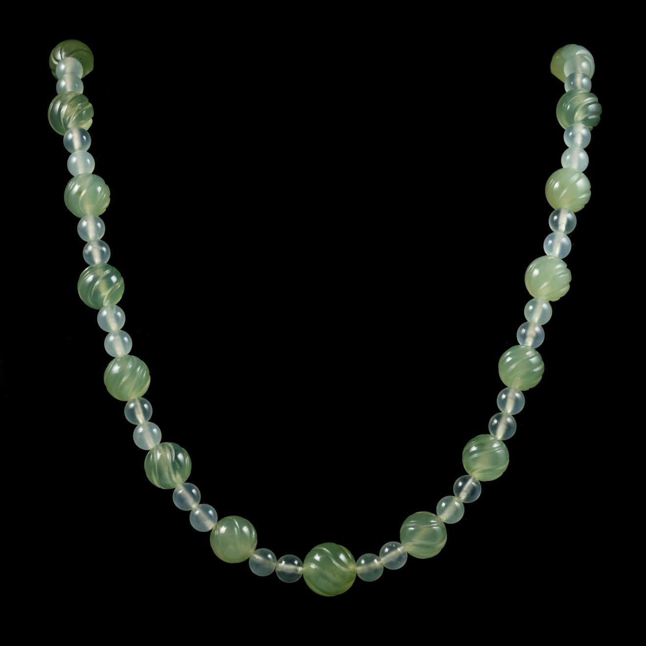This magnificent long antique Beaded Serpentine necklace is from the Victorian era, Circa 1900. The lovely necklace features apple green Serpentine beads which alternate in size with larger engraved beads decorated throughout. Serpentine derives its