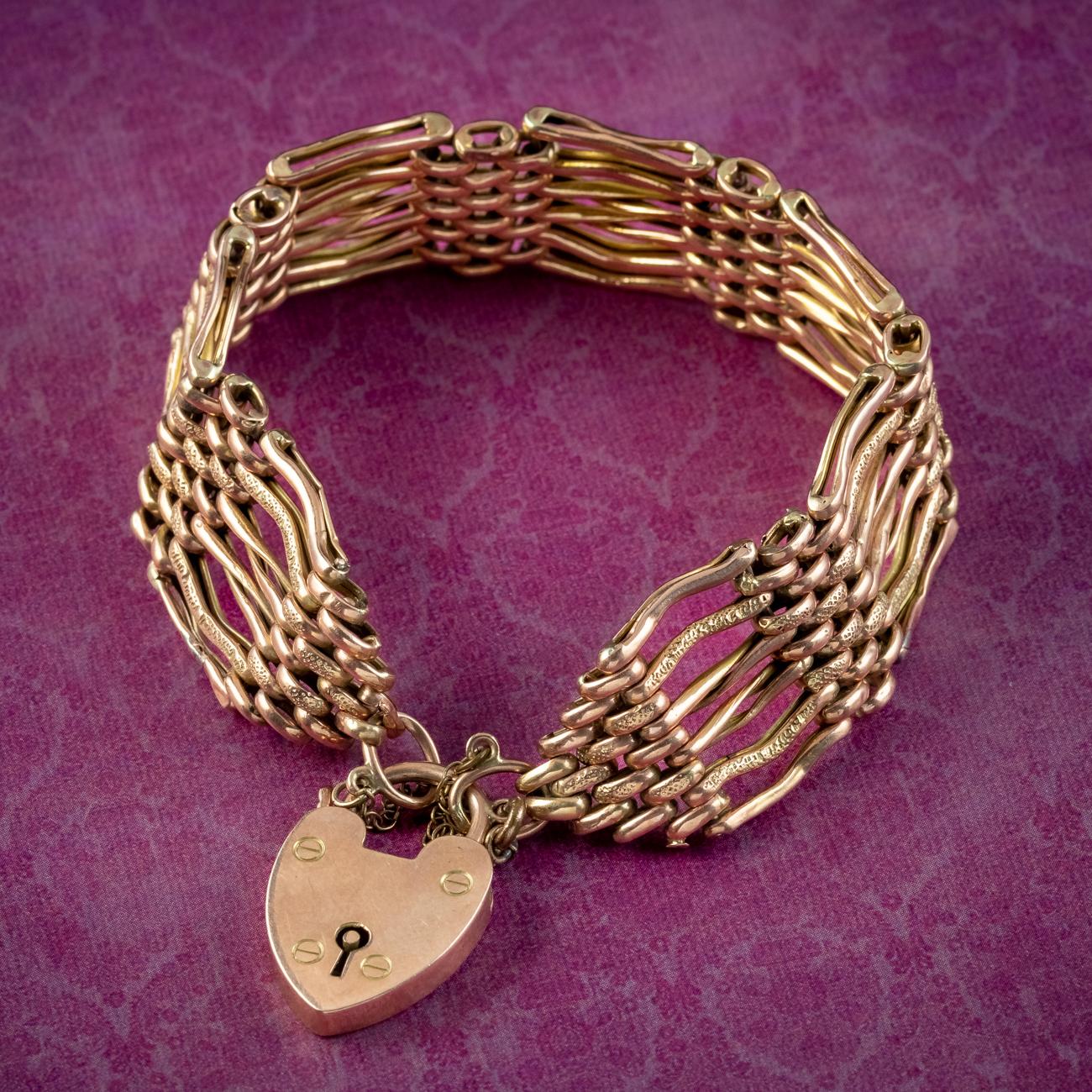 A grand antique Victorian gate bracelet from the late 19th Century fashioned entirely in 9ct gold. The wide band consists of twisted gate links etched with textured detailing and is held by a safety chain and large heart padlock clasp.

Heart