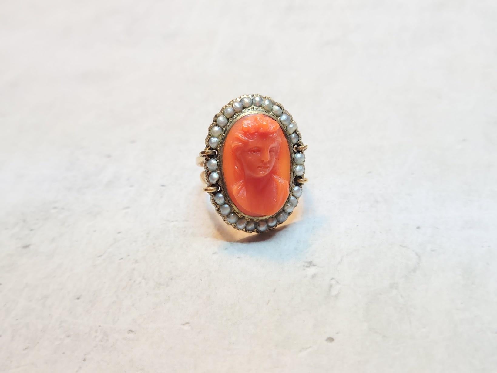 This charming 14kt yellow gold ring centers upon a genuine Mediterranean carved coral. The coral has been meticulously hand-carved and is surrounded by genuine seed pearls. The coral has beautiful color and richness and very high quality carving.