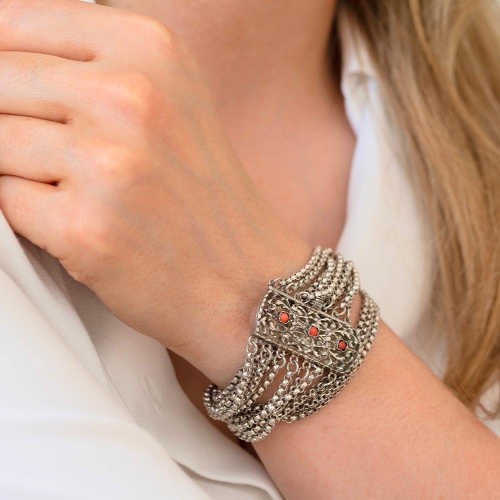 Questo antico braccialetto vittoriano è composto da sette fili di pregiato materiale.  catena d'argento, creando un bellissimo design a strati. Il bracciale si chiude con una fibbia decorativa a forma di scatola floreale con tre cabochon di corallo