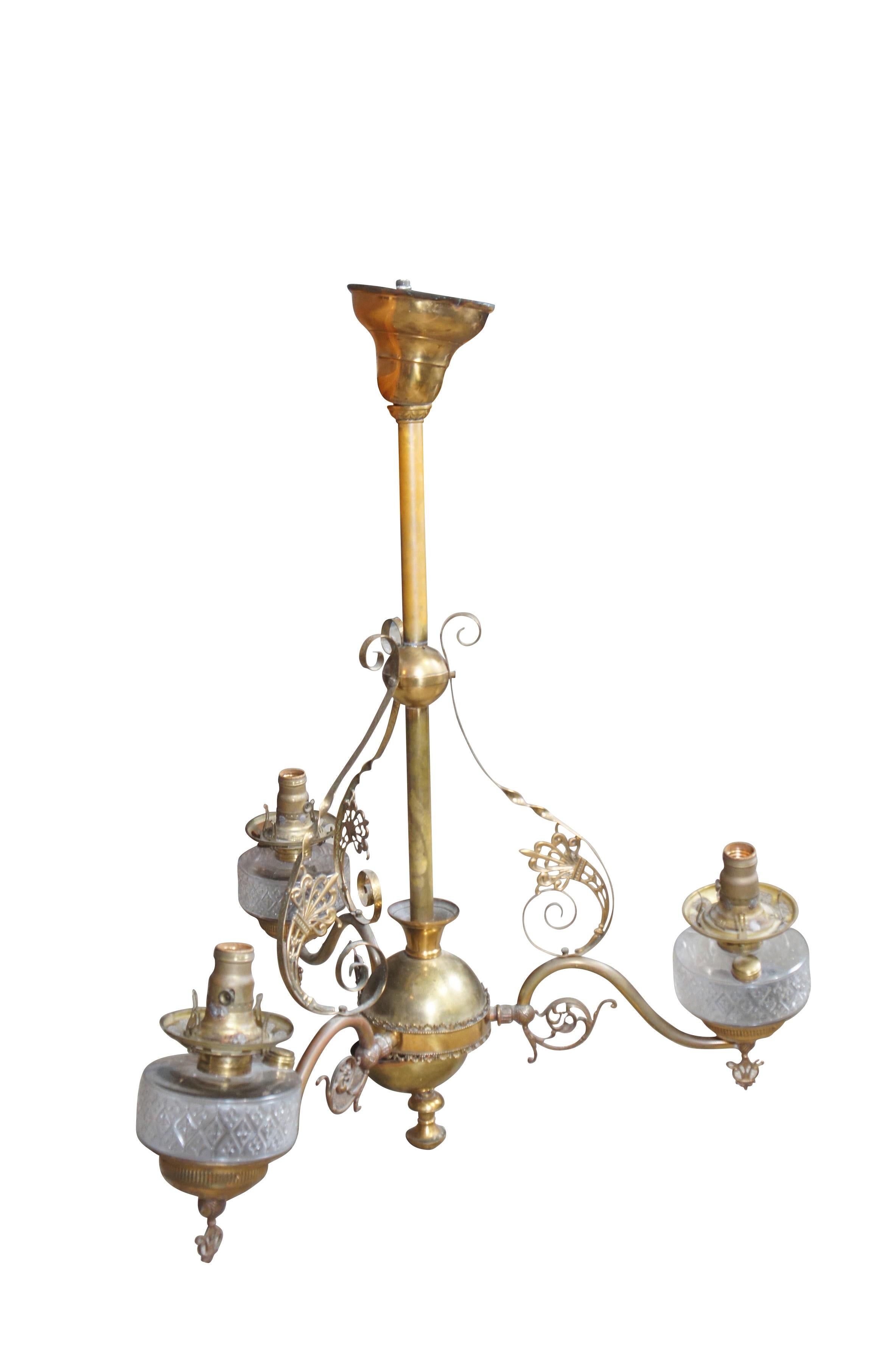 Lustre victorien ancien à trois bras en laiton  - comprend une base en forme d'orbe supportant trois bras en volutes menant à un trio de lampes à huile en verre à motifs floraux et de diamants.  Conversion à l'électricité.

Dimensions :
26