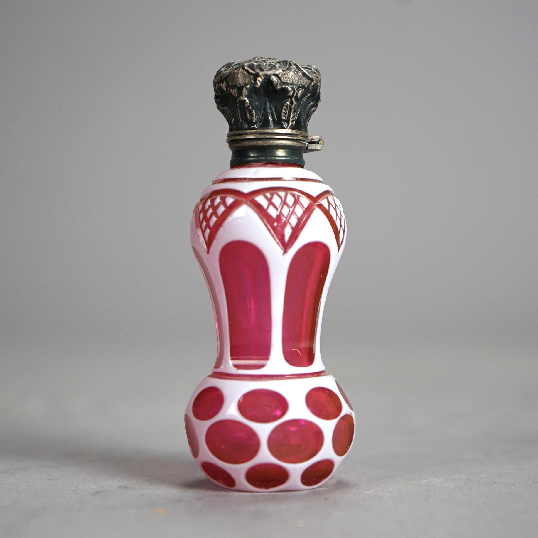 An antique Victorian perfume offers cranberry cut to clear art glass construction in stylized hourglass form having a foliate embossed cast flip-top lid, 19th century

Measures- 3.75''H x 1.5''W x 1.5''D