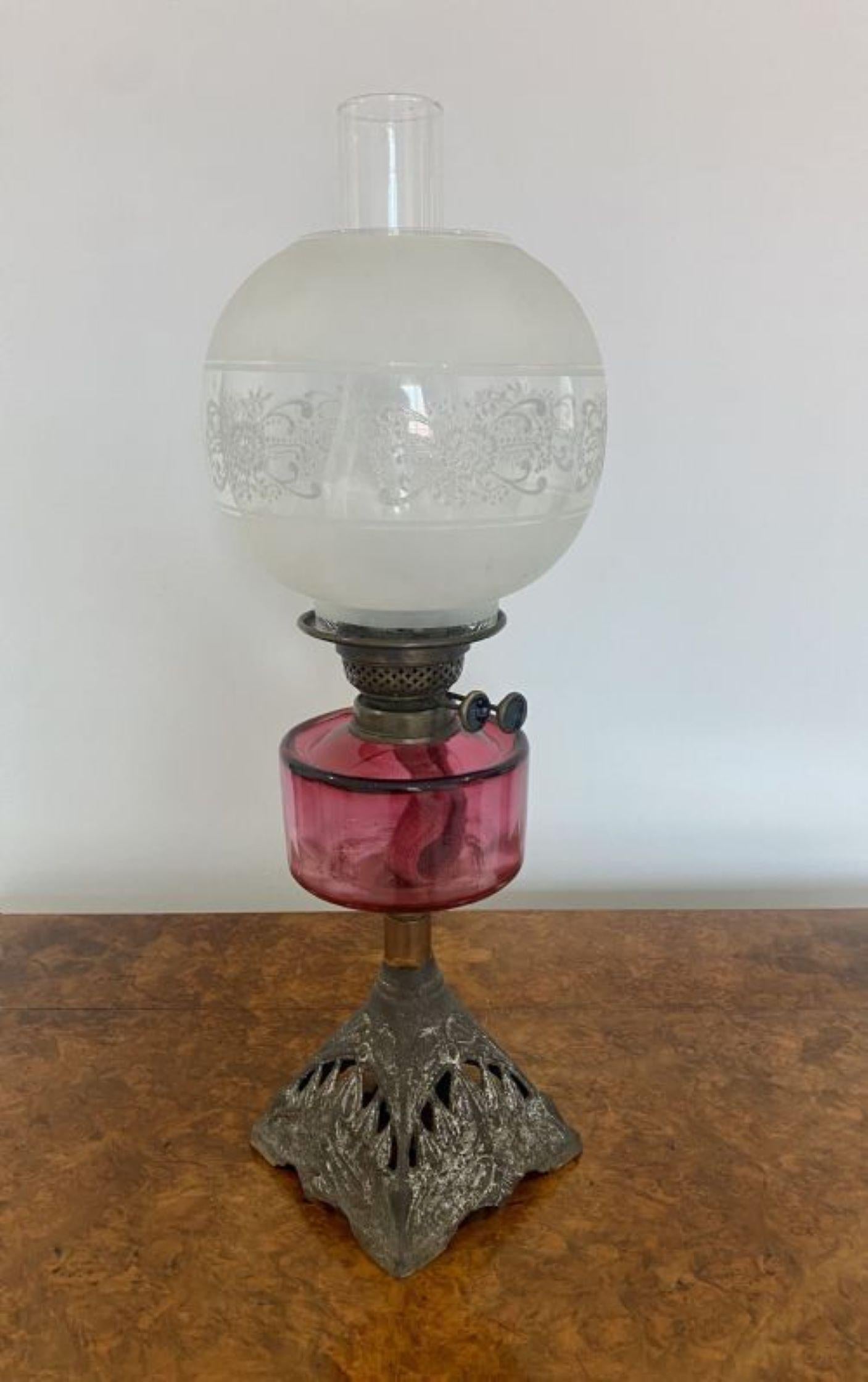 Antique Victorian cranberry glass oil lamp having a glass shade and chimney, double burner, cranberry glass font standing on a ornate iron base 