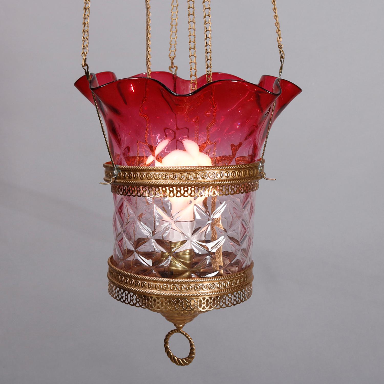 An antique Victorian hall light offers a suspended pierced brass frame housing an ombre cranberry to clear glass shade with diamond patterning and ruffled rim, electrified, circa 1890


Measures: 34
