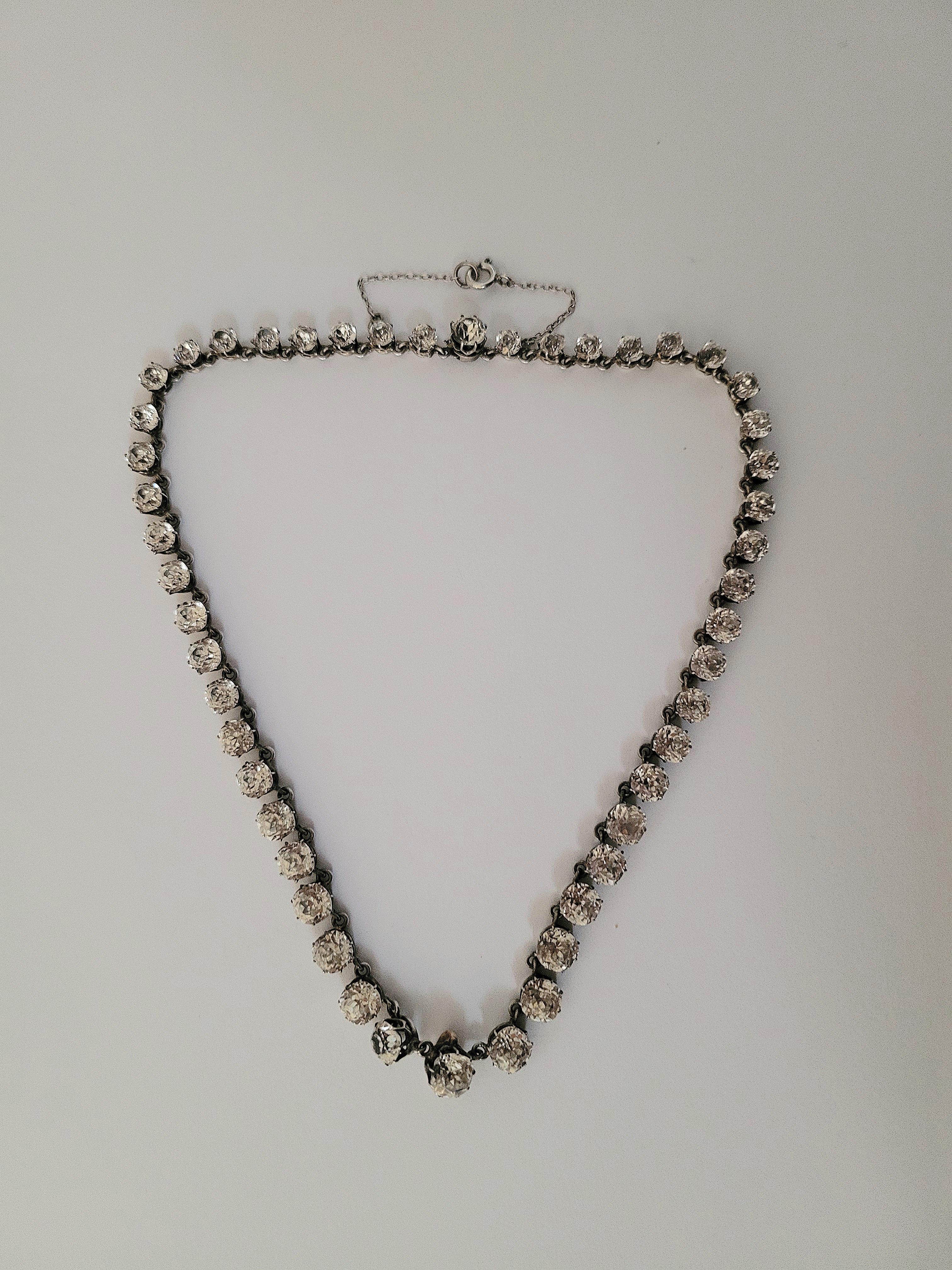 This exquisite Victorian c.1800s Silver and Cushion Paste RIVIERE Necklace radiates timeless elegance. The meticulously crafted piece boasts a stunning array of paste stones, each enhanced by a silver-colored backing for added brilliance. Set in an