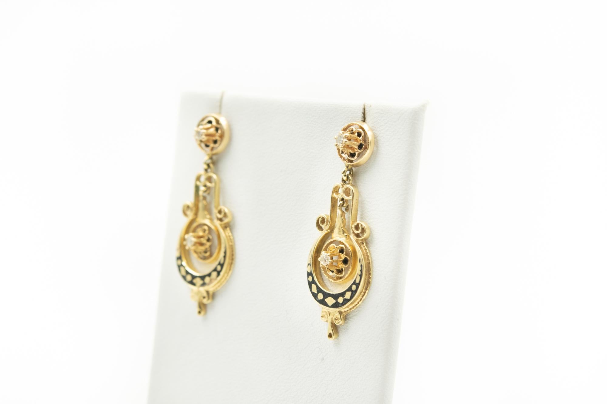 Beautiful pair of Victorian drop earrings made of 10k yellow gold with black enamel accents and single cut diamonds.  The post is attached to a gold flower with black enamel petals and a diamond center.  A similar piece dangles in the center of the