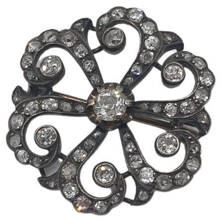 Antique victorian era 1850.c brooch in a circular designe centered with old mine cut diamonds flanked with old mine cut diamonds with estimate weight of 1 carat in 10k gold topped with silver and open work style 