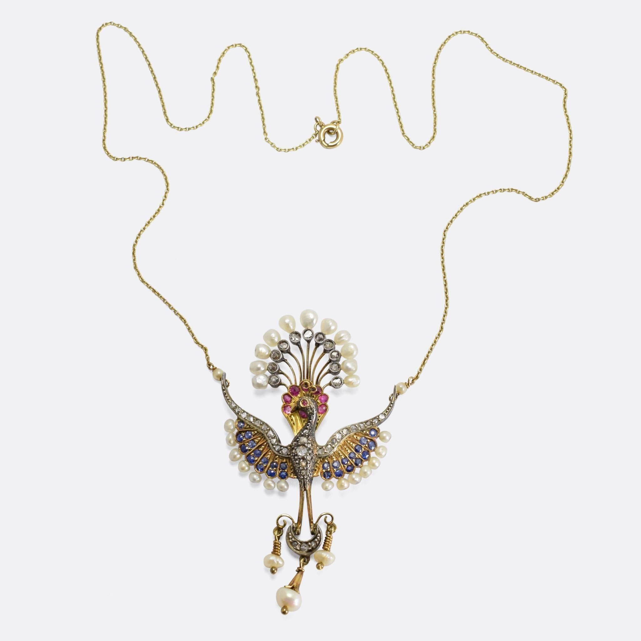 A truly stunning antique necklace modelled as a Peacock in full display. It’s set with a combination of diamonds, blue sapphires, rubies, and baroque pearls – the gemstones rest in silver millegrain settings, and the piece is modelled in 18k gold