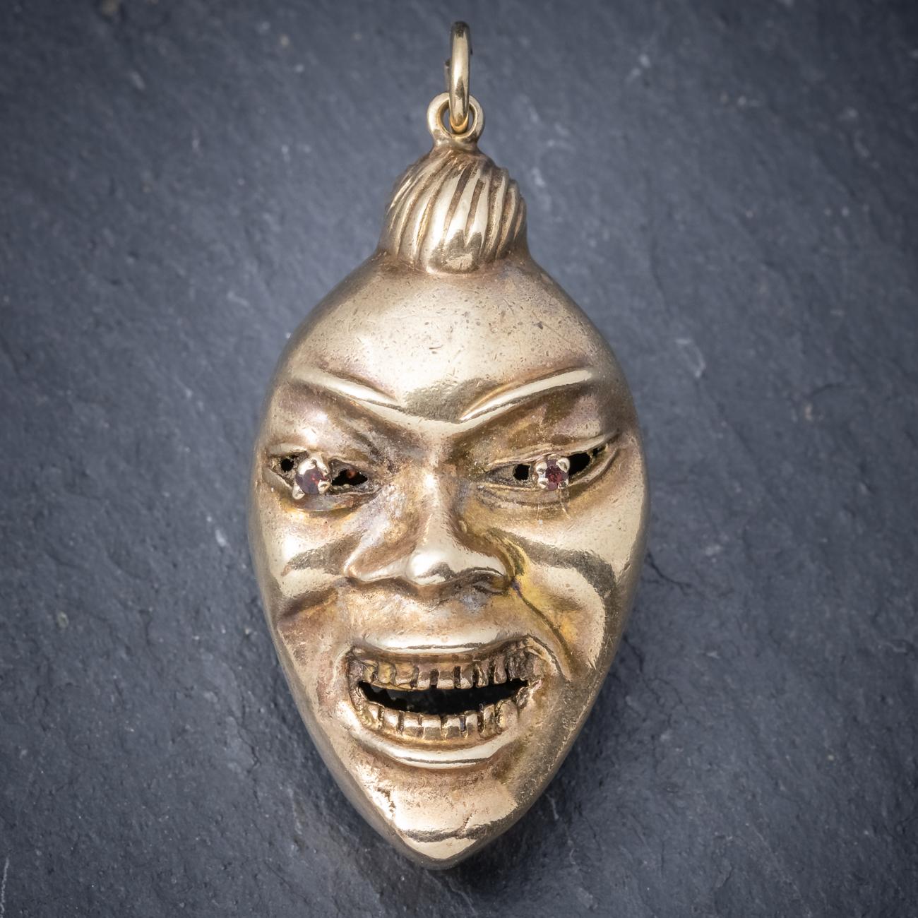 A curious antique Victorian pendant featuring two engraved faces on the back and front set with red Garnet eyes. The faces are full of character and appear to be laughing with wide grins on their faces. Set in 9ct Yellow Gold and complete with