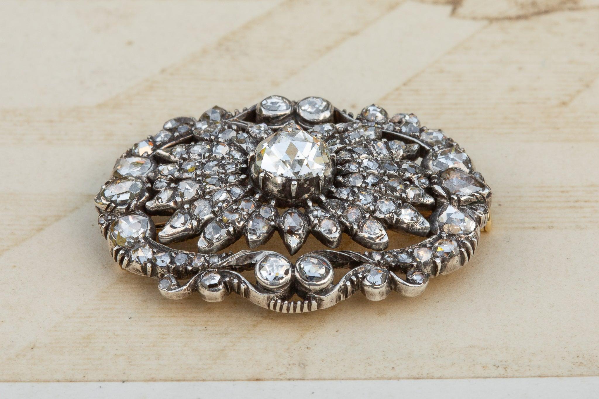 An exquisite late 19th-century Dutch brooch, intricately set with over 100 rose-cut diamonds. The design centres around a large diamond measuring 6mm across, surrounded by a floral cluster of countless smaller stones, all enhancing its stunning