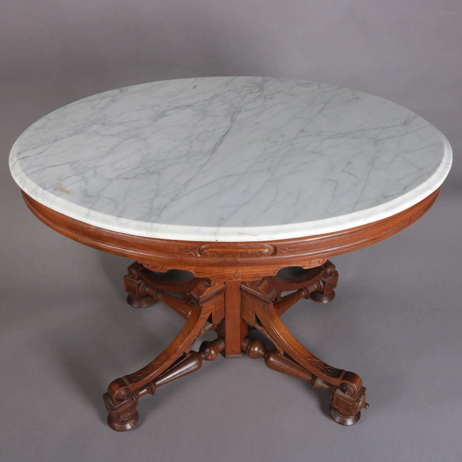 Antique Eastlake Victorian carved walnut parlour table features carved and incised apron supporting bevelled marble top, raised on elaborate pedestal with scroll, turned and incised elements, 19th century.

Measures: 20