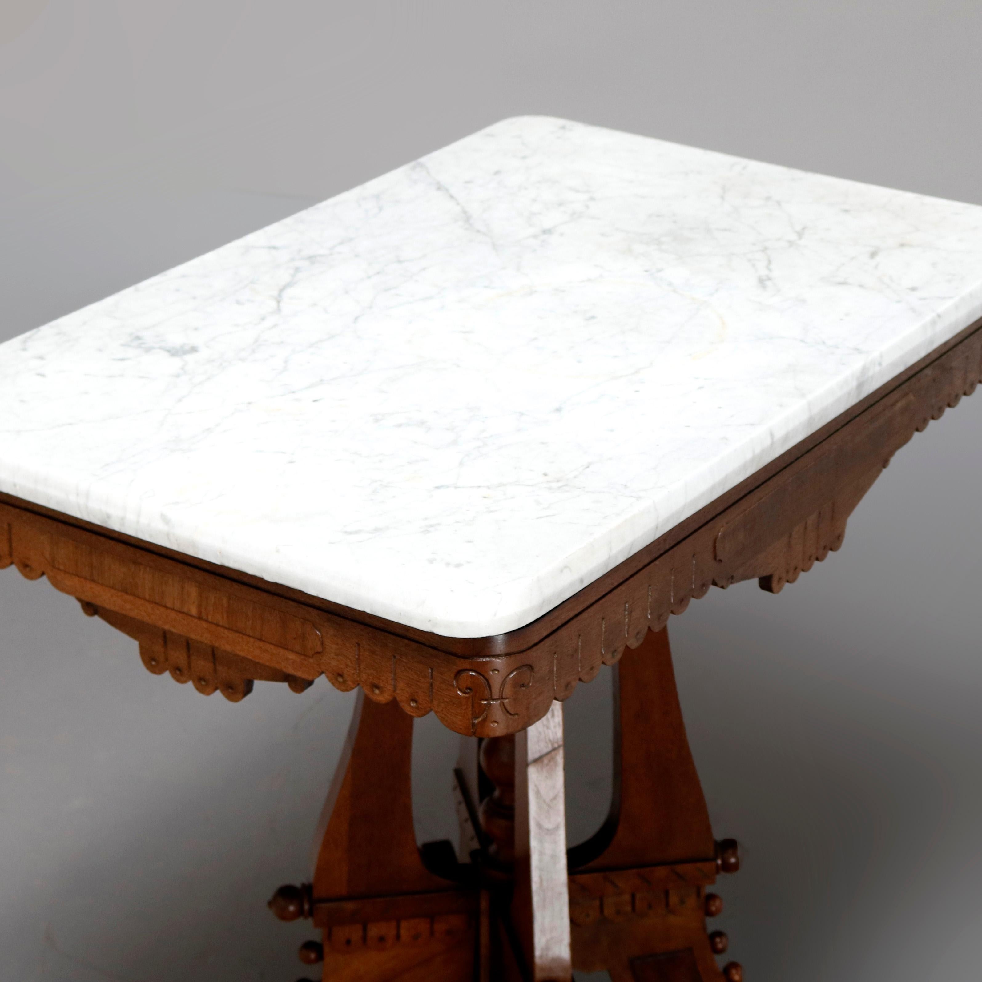 An antique Victorian Eastlake side table offers a beveled rectangular marble top surmounting carved walnut frame having shaped and incised scalloped skirt raised on shaped legs with burl and ball bead accoutrements surrounding turned central column