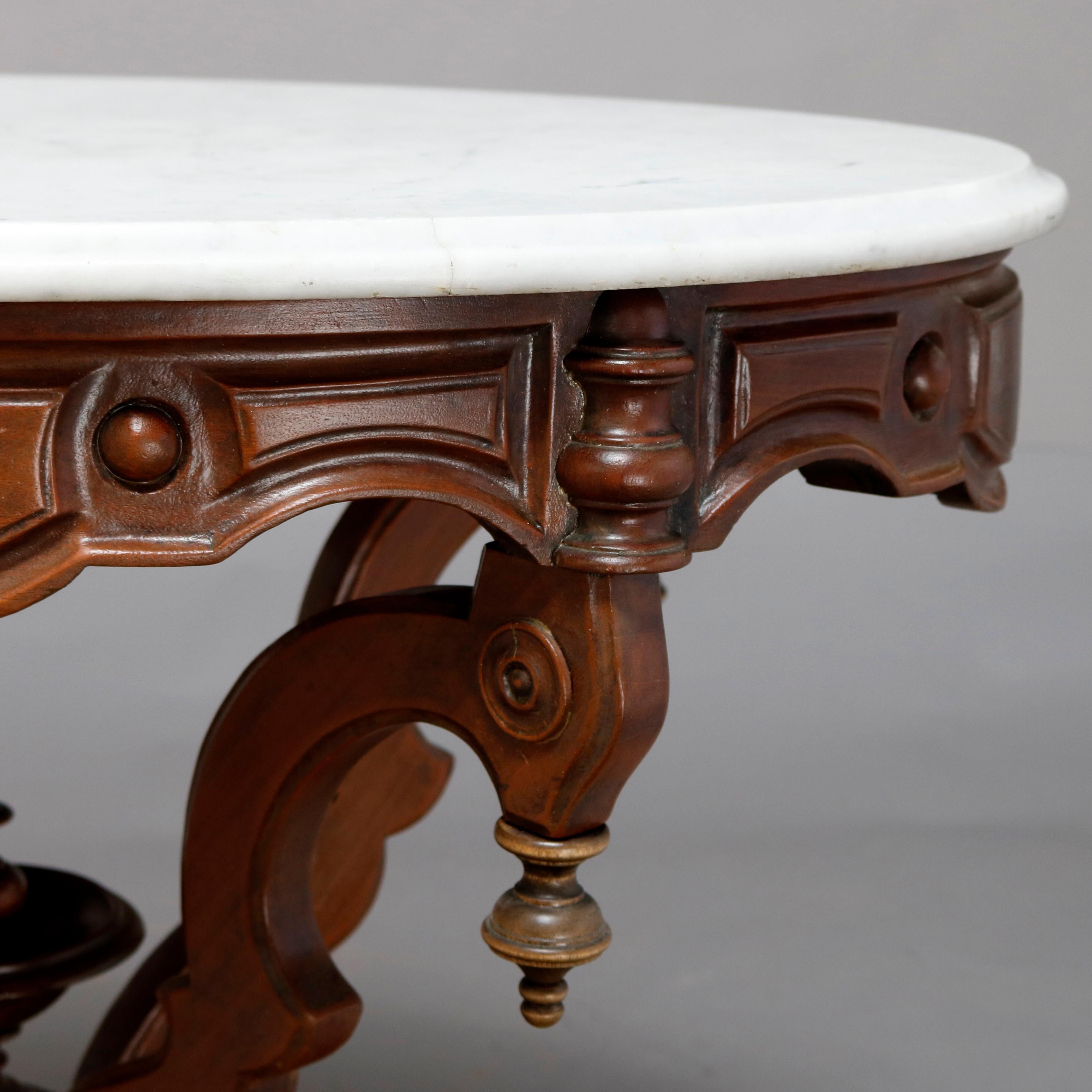 An antique Victorian Eastlake side table offers a beveled oval marble top surmounting carved walnut frame having paneled skirt raised on s-scroll legs with drop finials and central urn form finial, circa 1880

Measures: 28.5