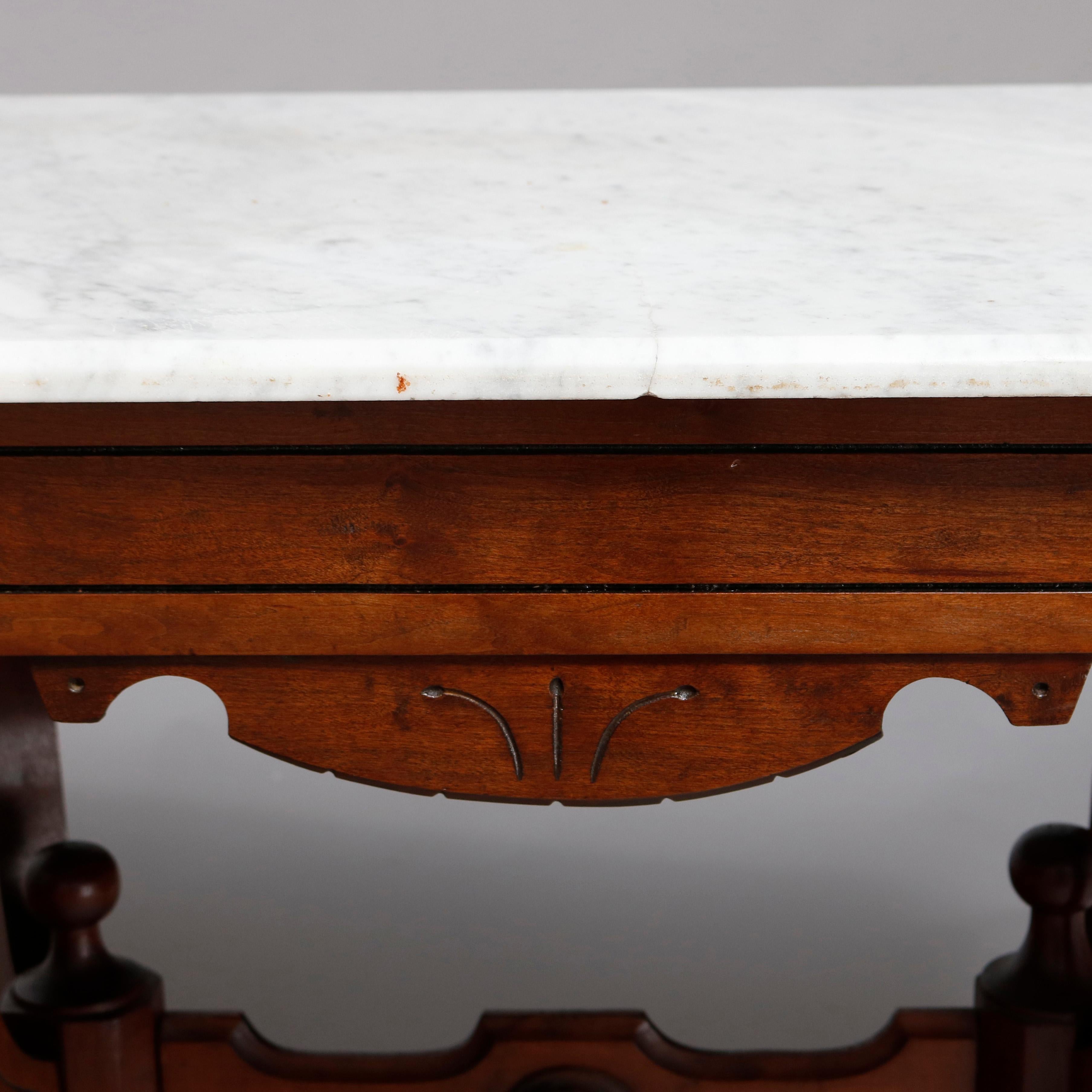 An antique Victorian Eastlake side table offers a beveled clip-corner rectangular marble top surmounting carved walnut frame having shaped skirt, raised on shaped legs with central turned and drop finials, circa 1880

Measures: 29.25