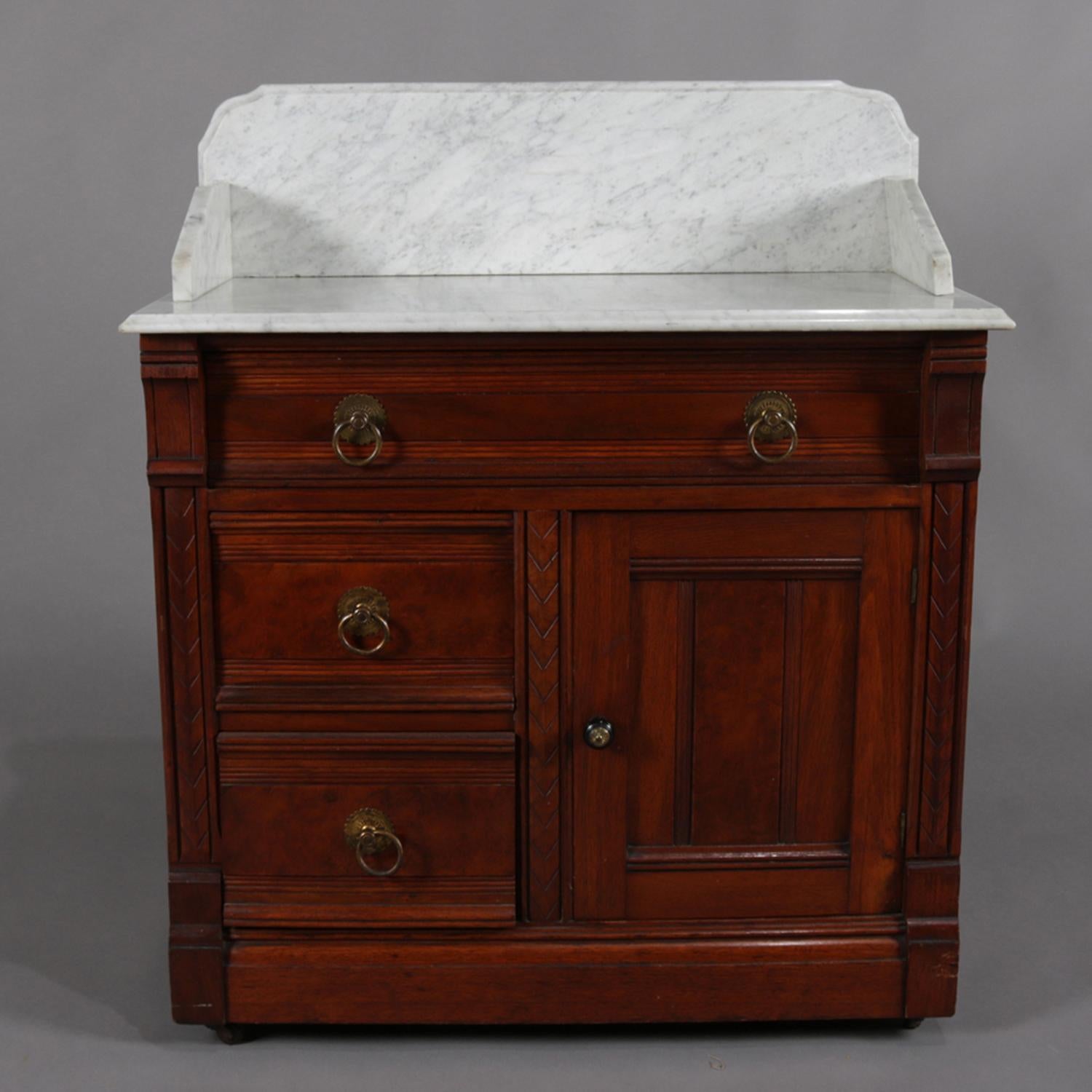 Antique Eastlake Victorian wash stand features marble-top with backsplash above walnut base having frieze drawer over two smaller drawers and side cabinet, circa 1890.

Measures - 37