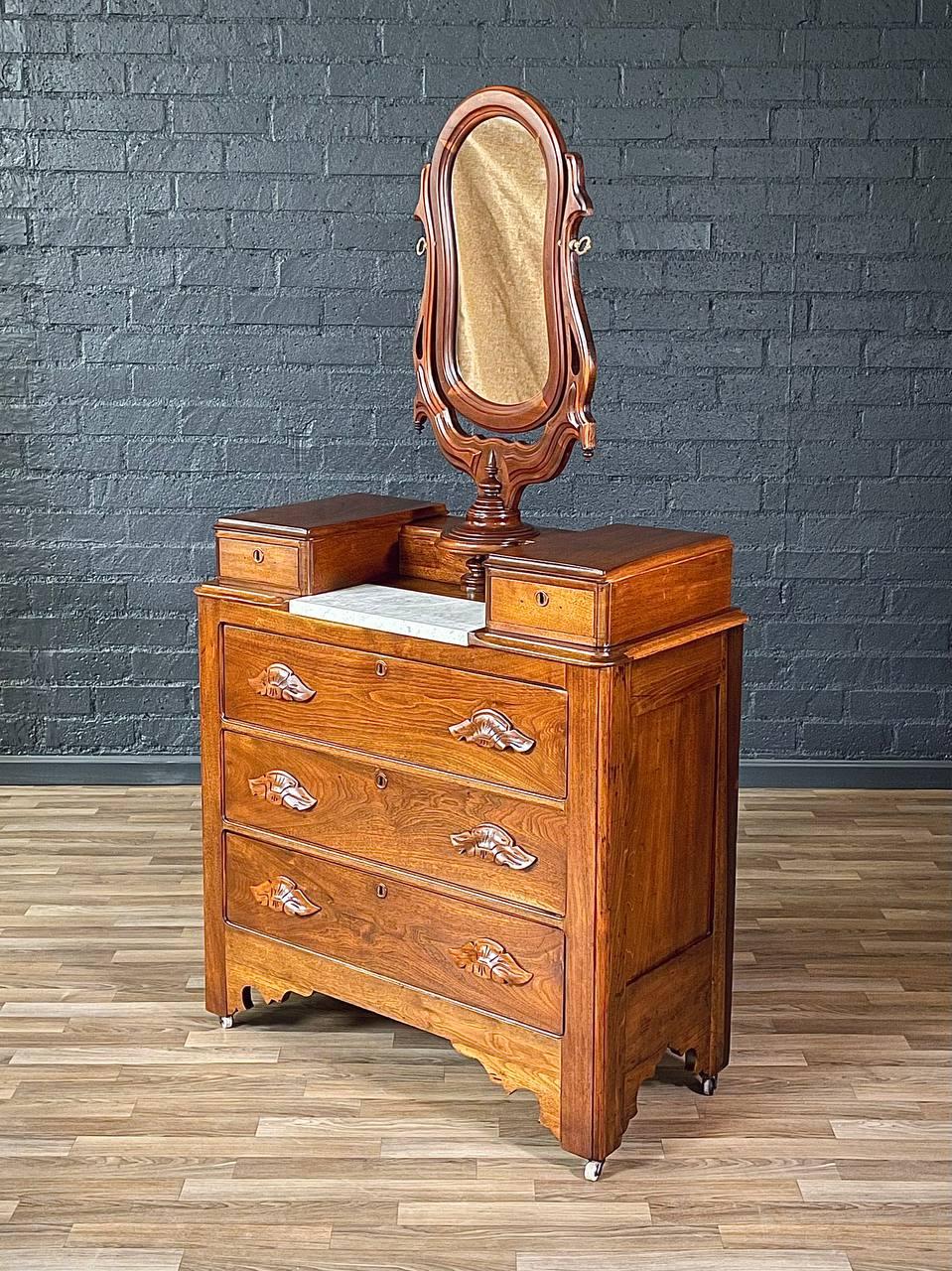 Condition: Original Vintage Condition

Materials: Carved Walnut, Carrara Marble, Original Mirror, Brass Hardware

This Victorian Eastlake dresser is a masterful blend of elegance and craftsmanship, featuring solid carved walnut and a white Carrara