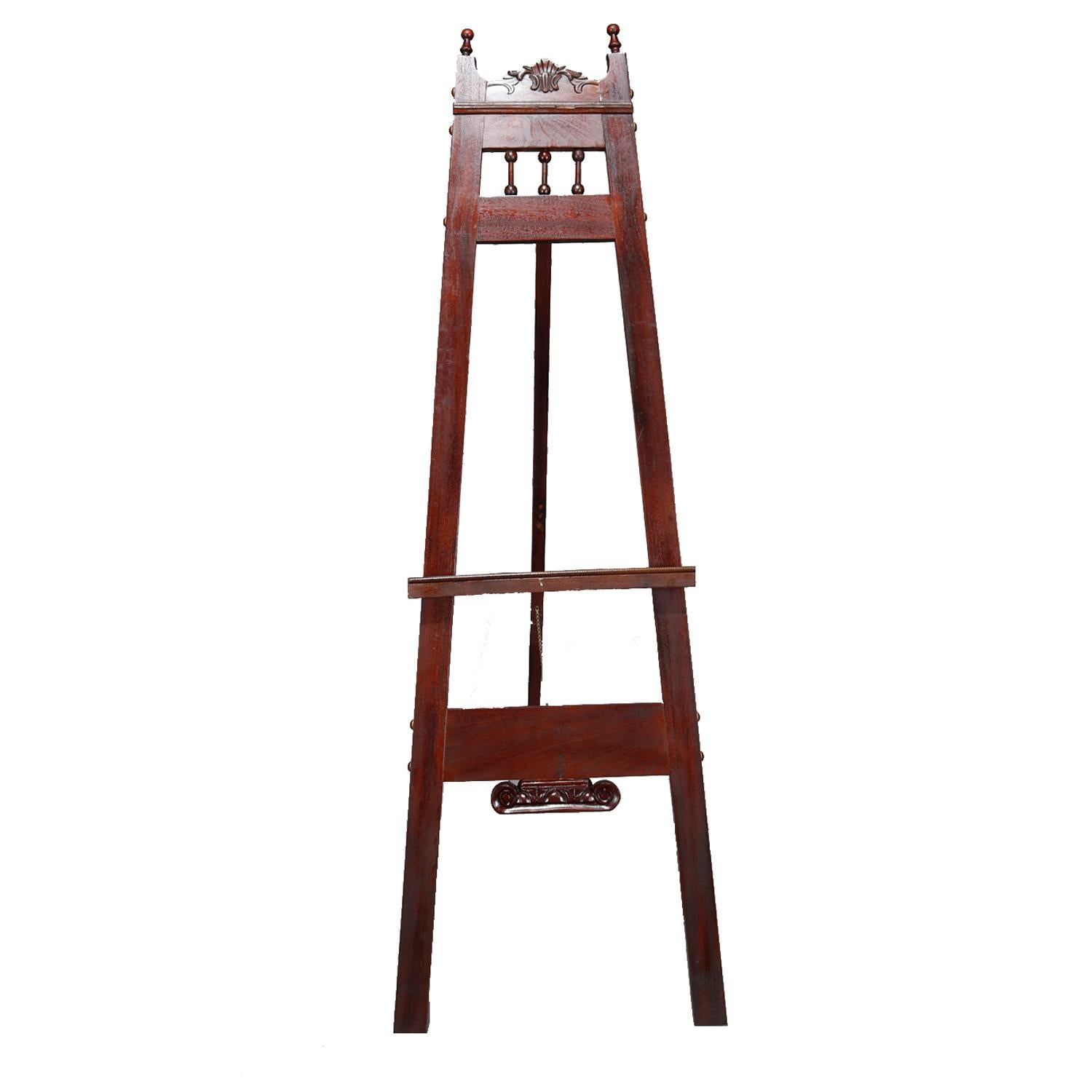 An antique Victorian Eastlake art easel offers walnut construction with carved stylized shell and foiate crest with flanking turned finials and surmounting stick and ball rail, circa 1880

Measures: 63